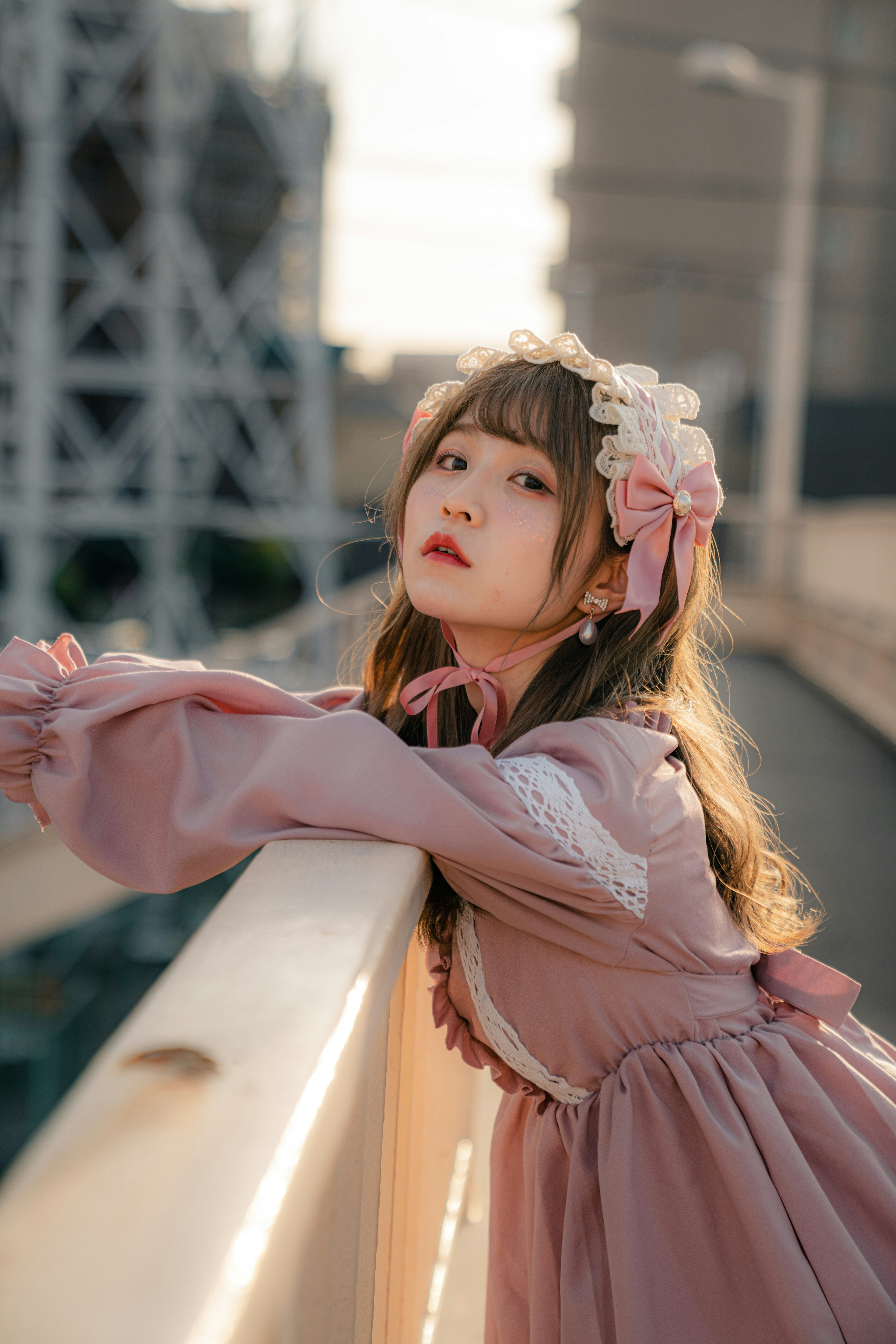 A girl in lolita fashion leaning on a balcony with a sunset background