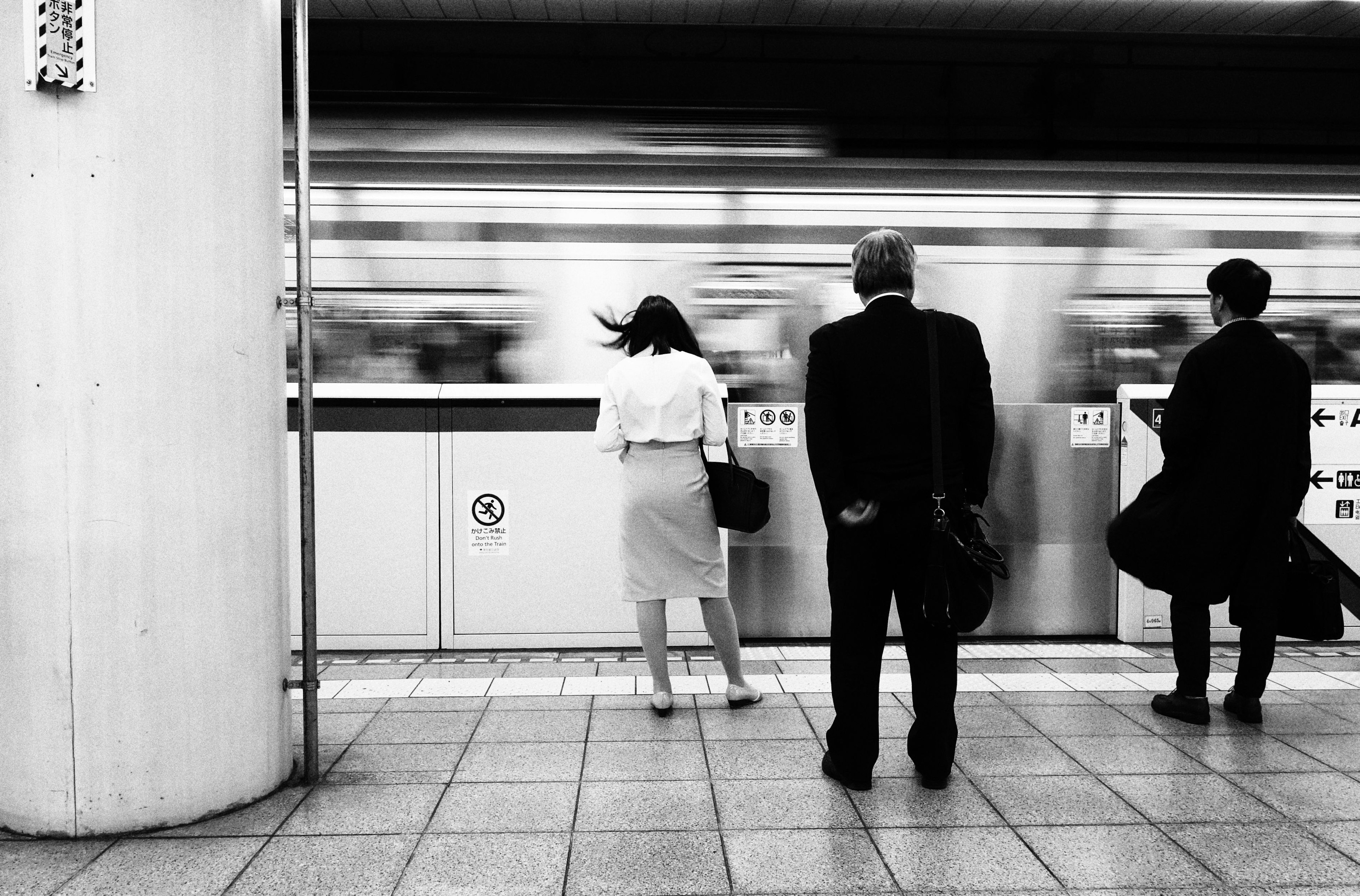 Black and white photo of people waiting at a subway station