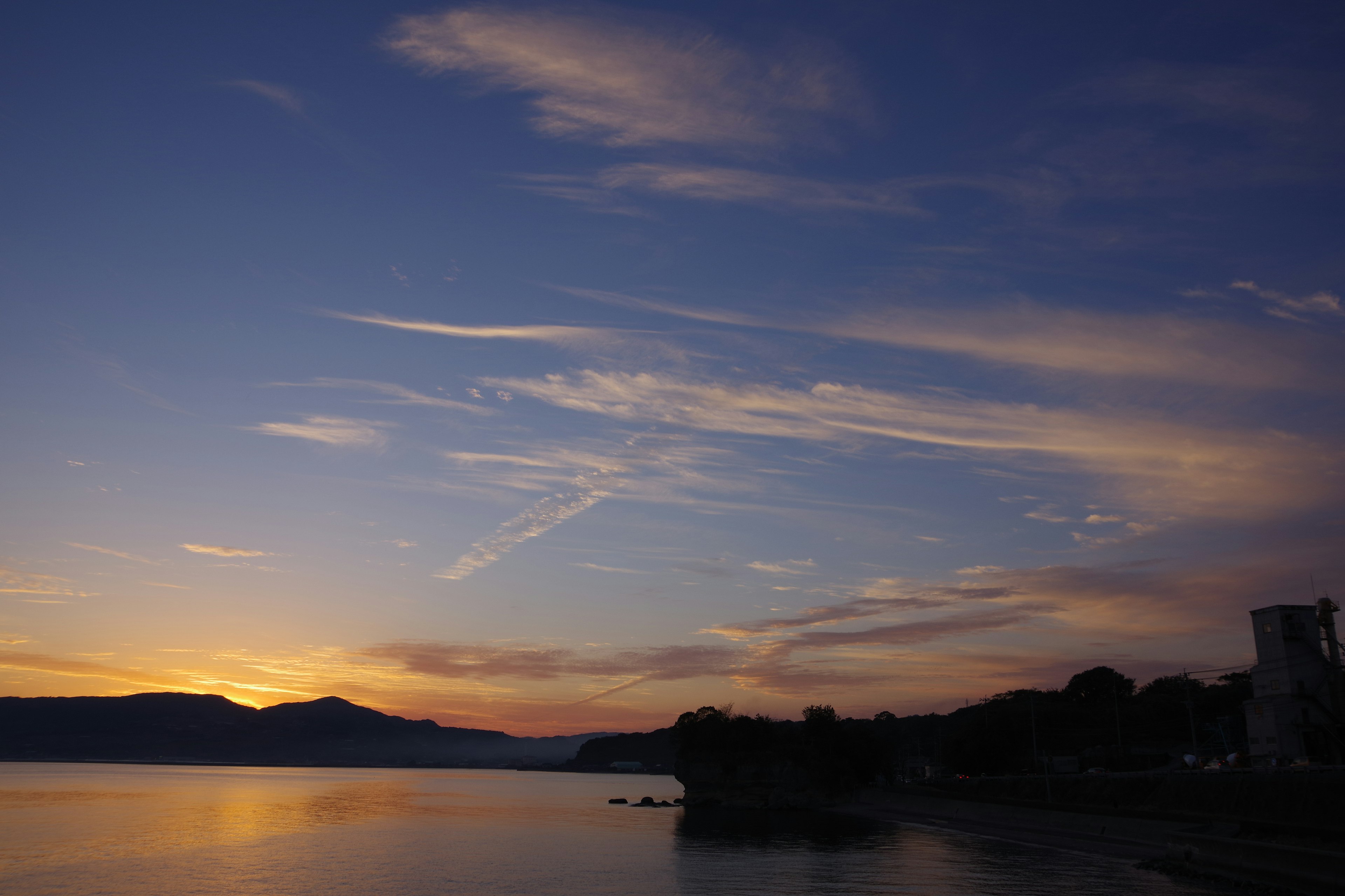 Sunset over a lake and mountains calm water surface and beautiful clouds