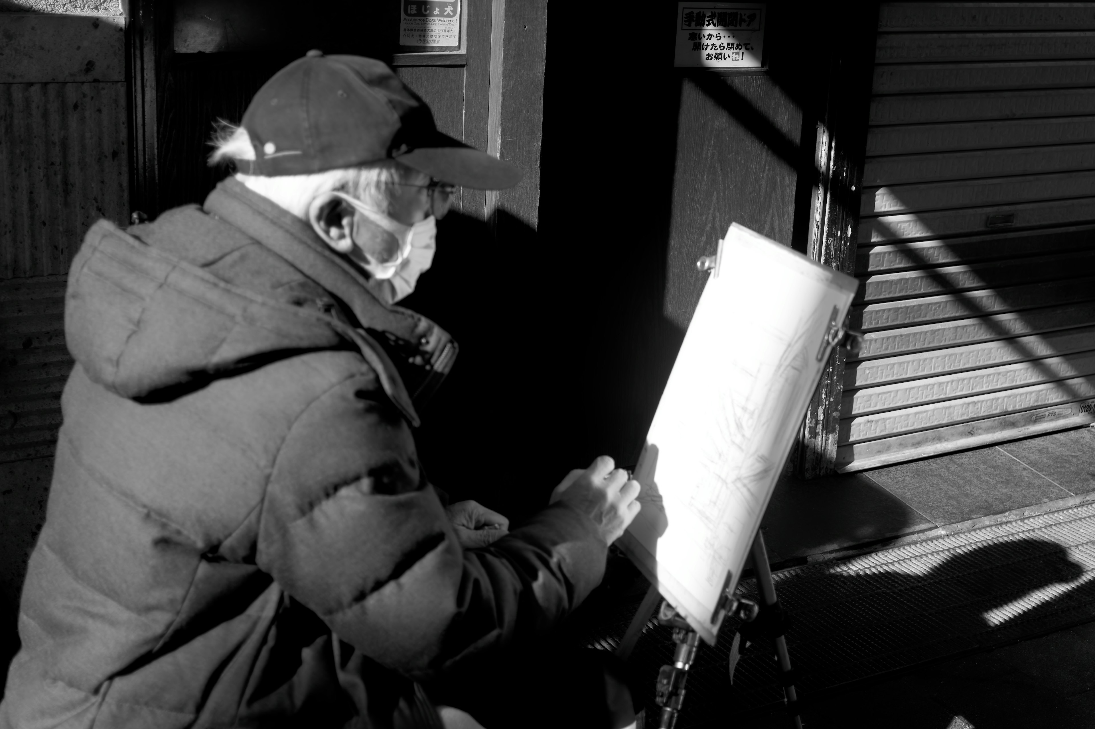 Hombre anciano con mascarilla dibujando al aire libre