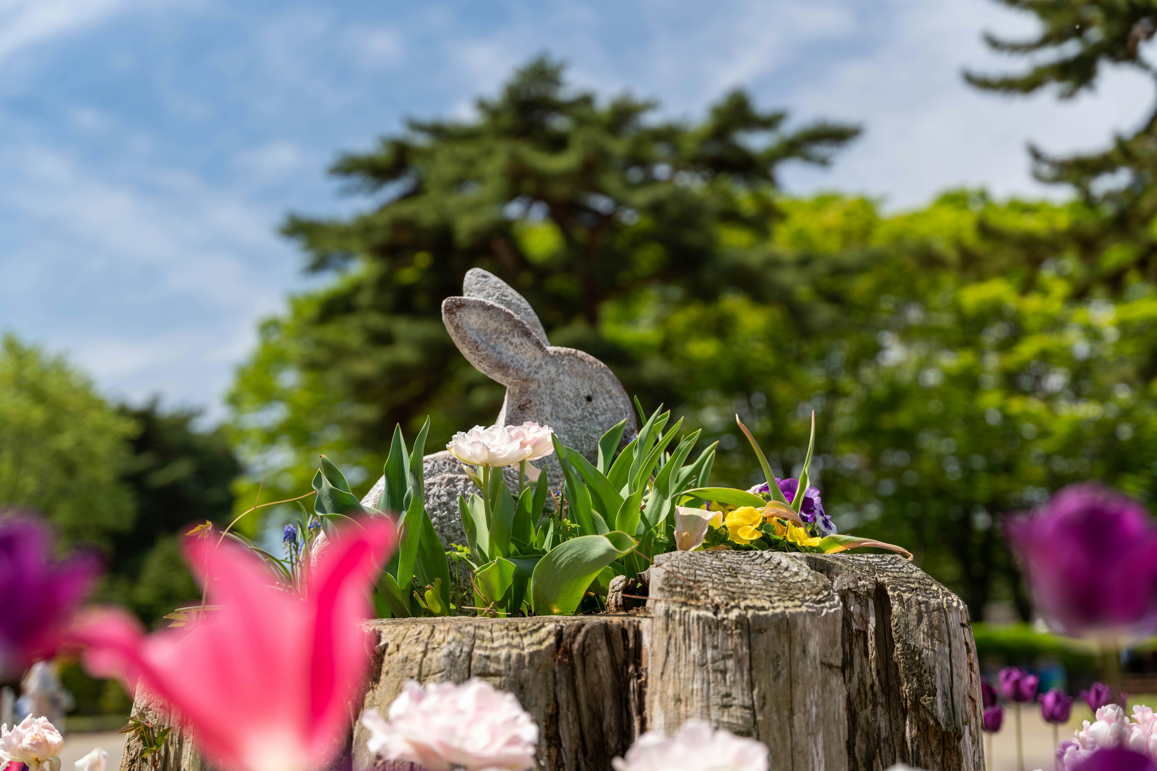 A rabbit sculpture surrounded by colorful flowers in a park