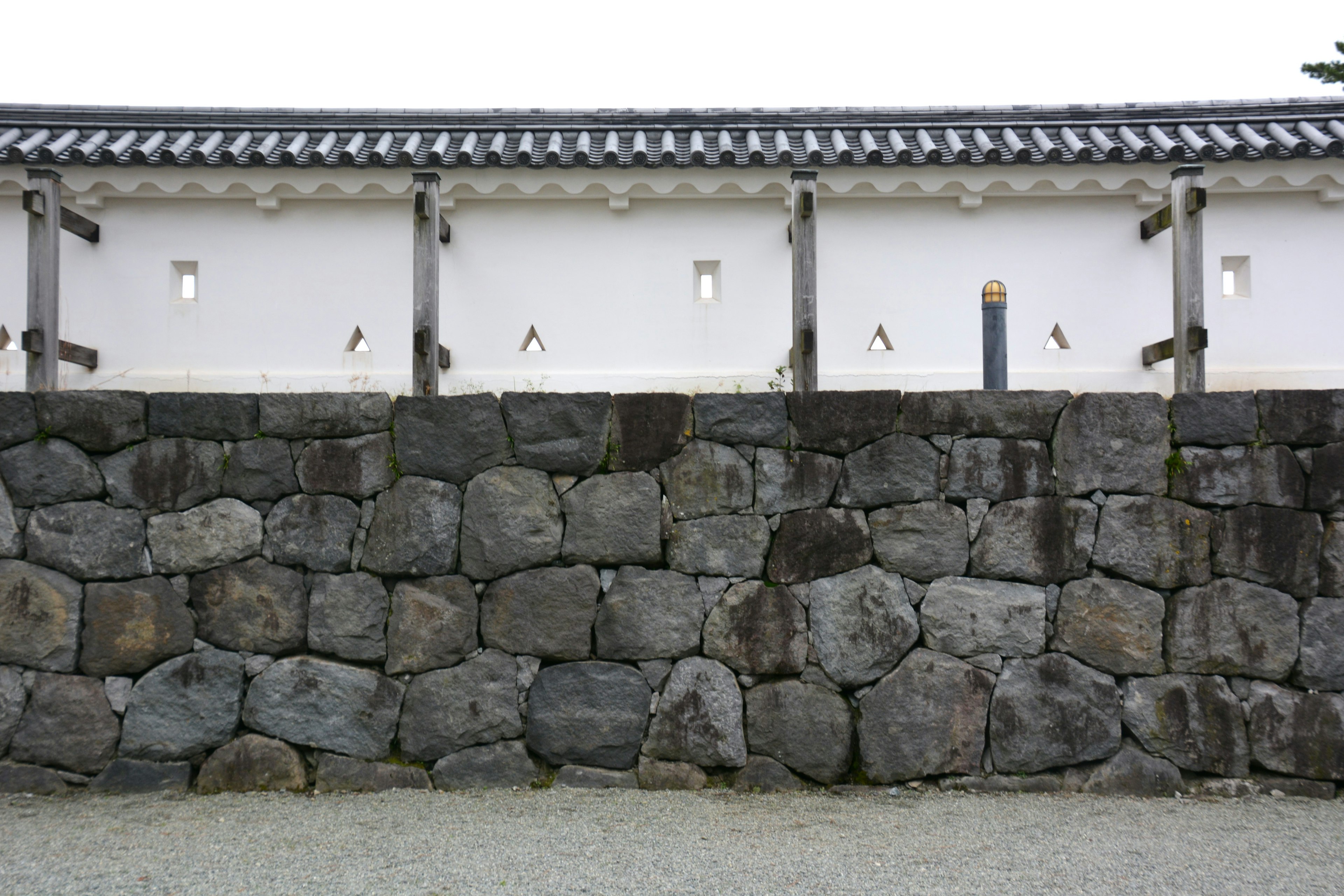 Traditional Japanese architecture featuring a stone wall and white fence