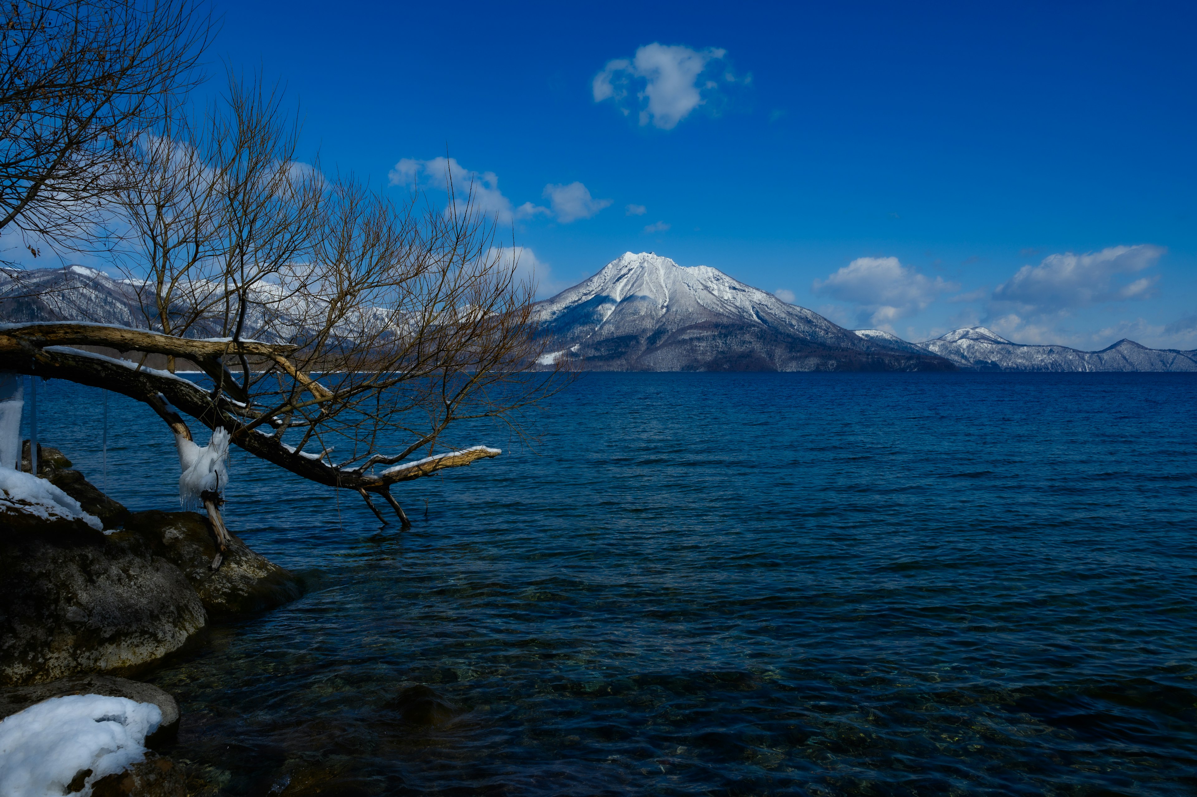 雪に覆われた山々と青空の下の静かな湖の風景