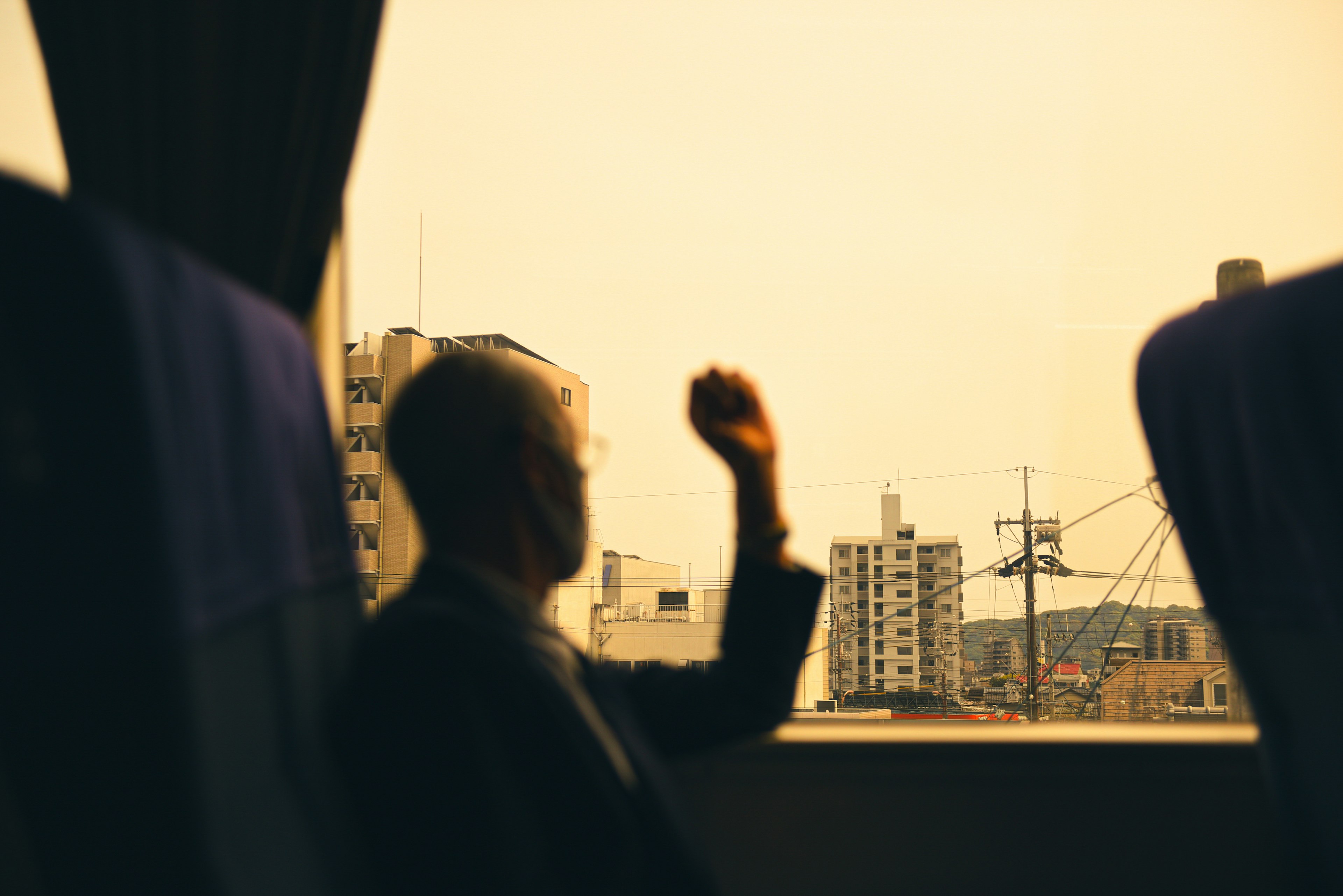 Silhouette di una persona che guarda fuori dalla finestra con un paesaggio urbano al tramonto