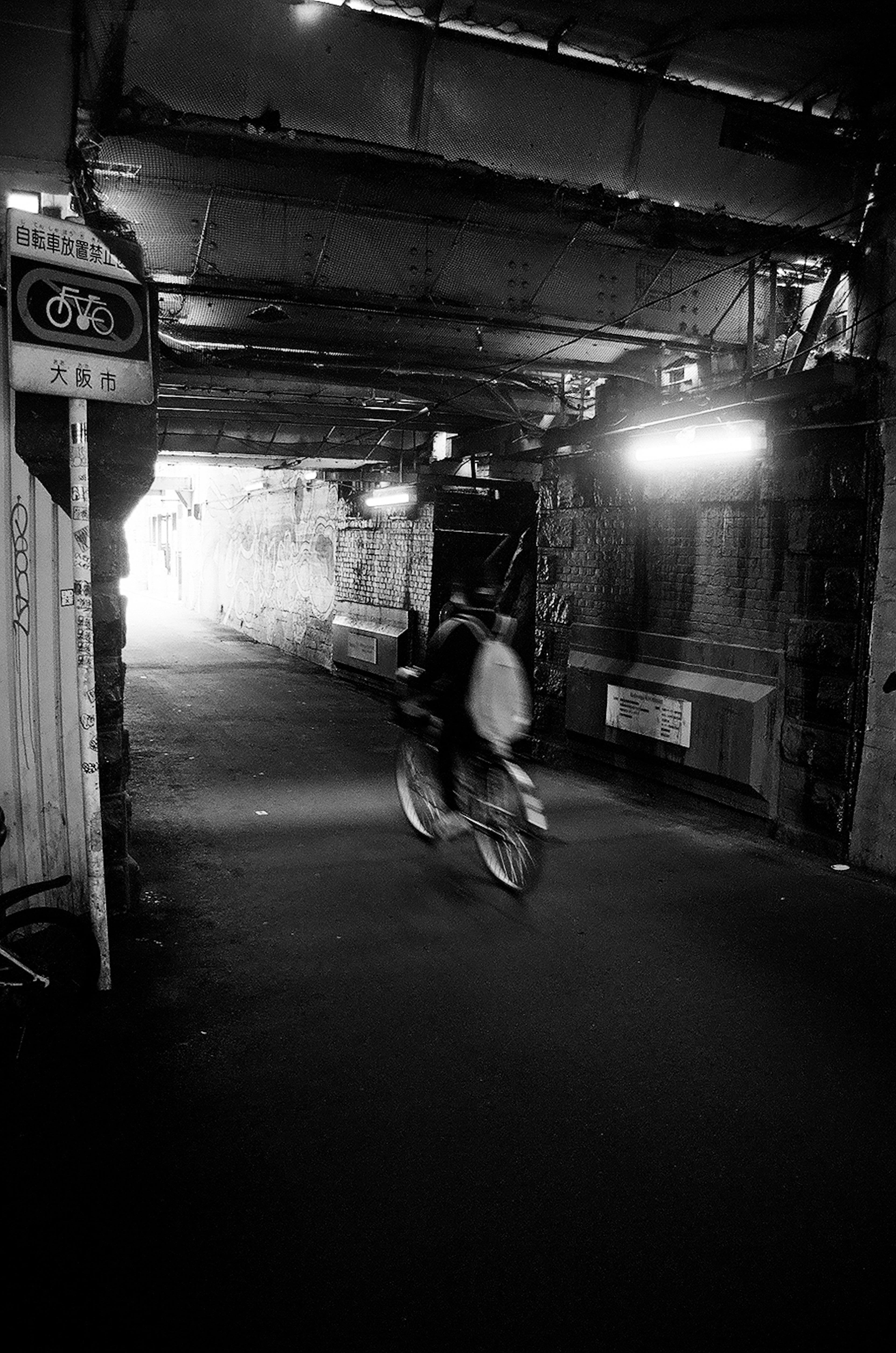 Silhouette of a person riding a bicycle through a black and white tunnel