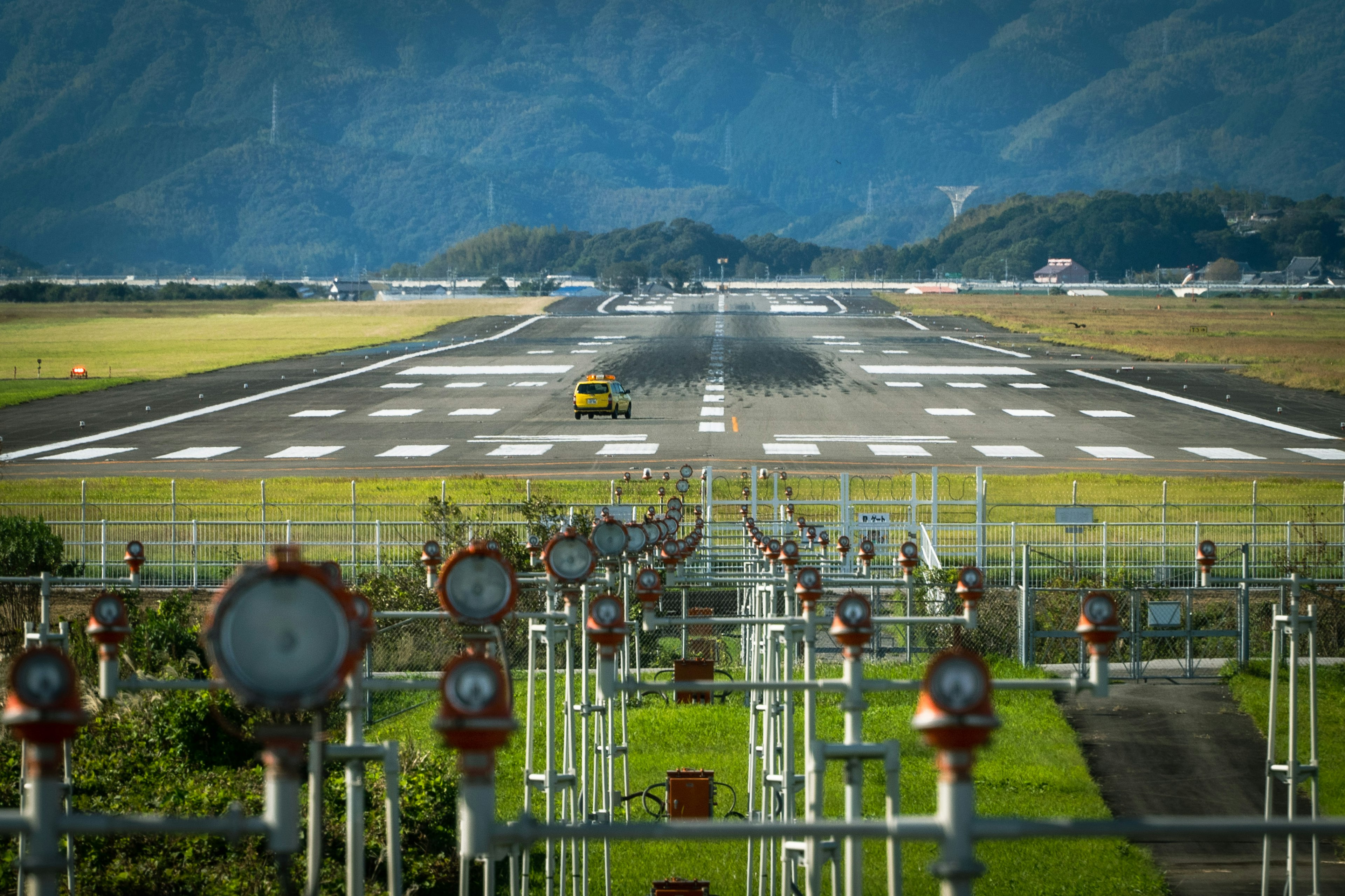 滑走路に沿った赤い信号機と黄色いタクシー車両の風景