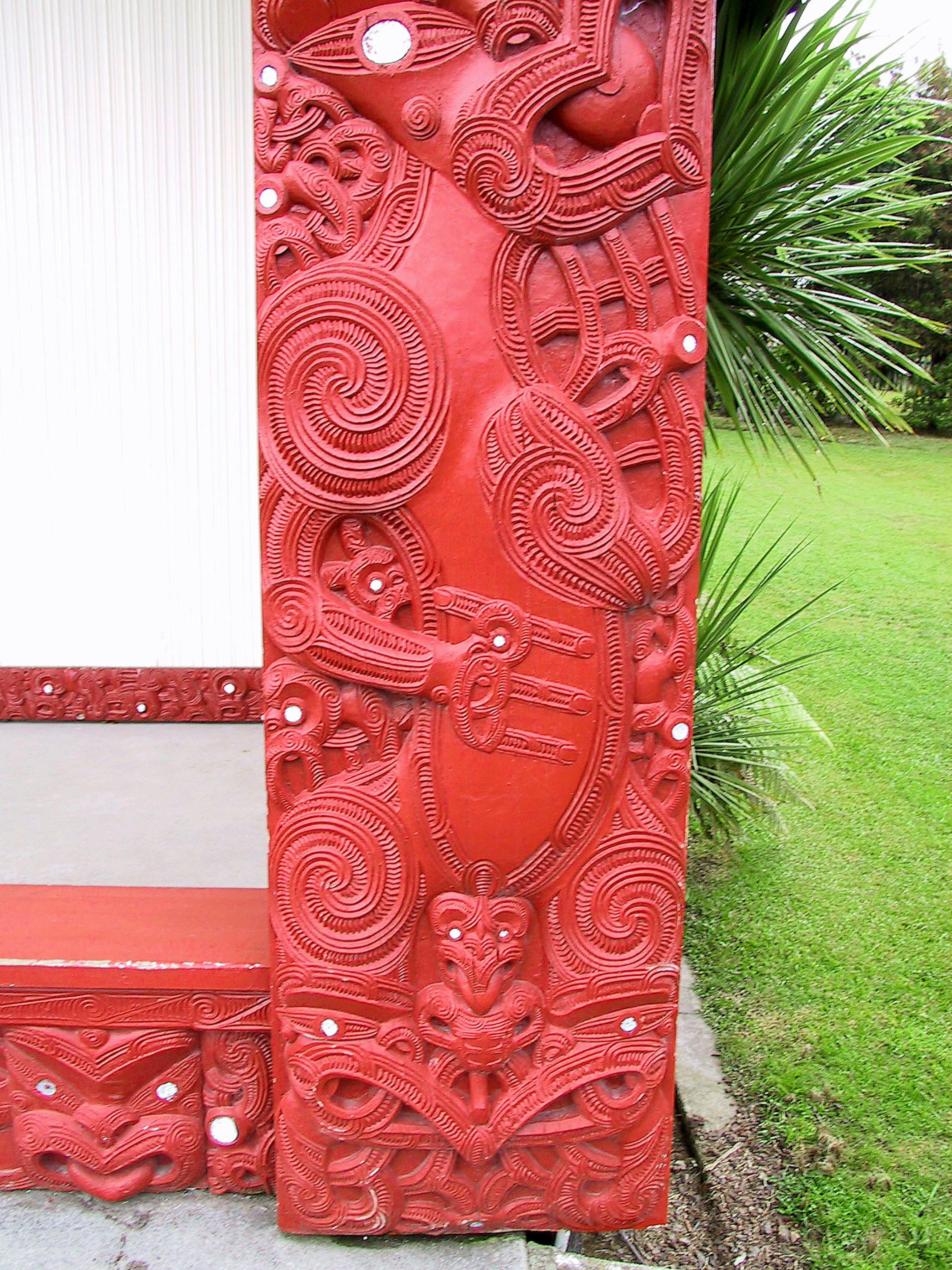 Traditional building corner with intricate red carvings depicting natural elements and cultural symbols