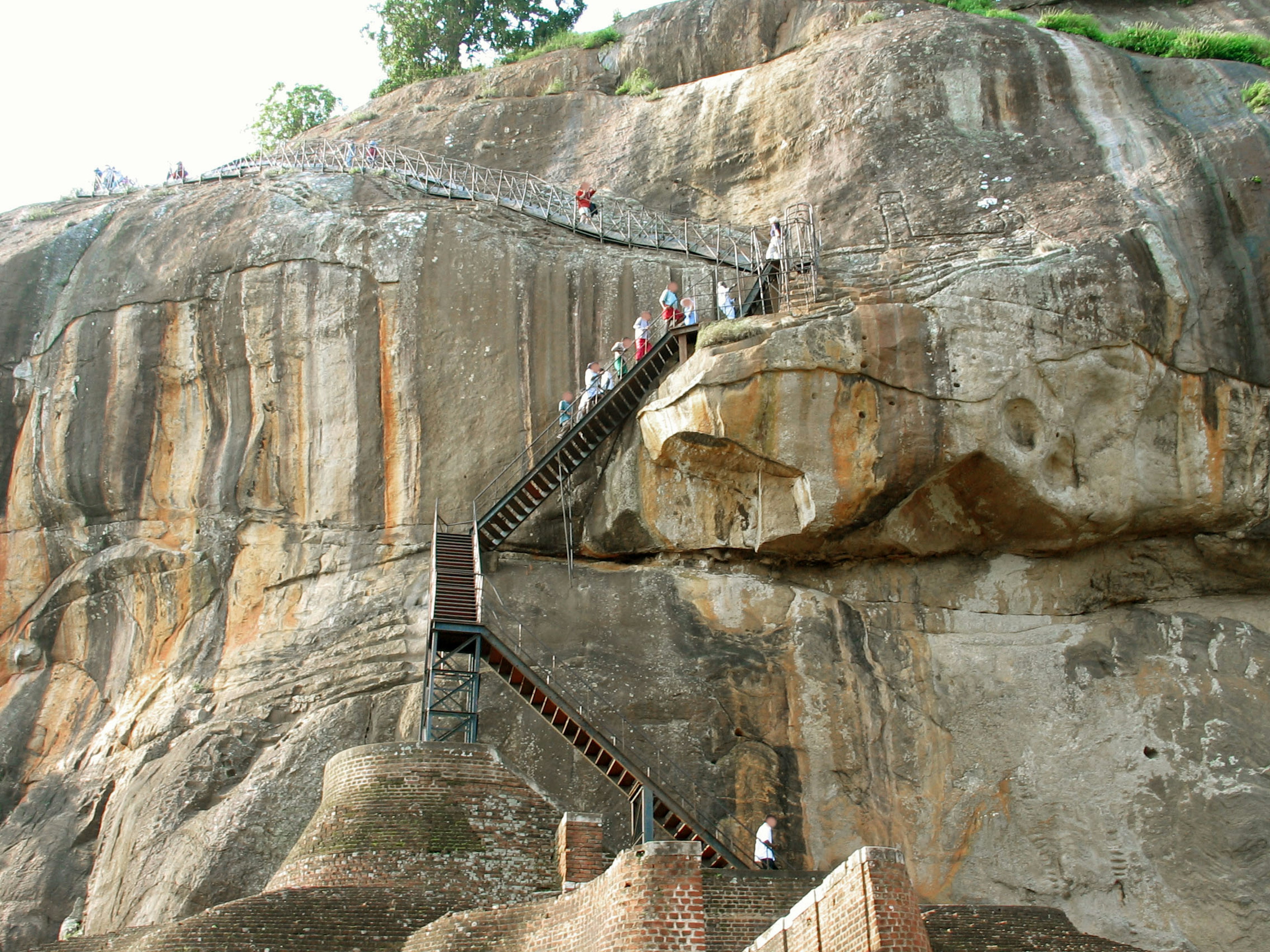 Eine Aussicht auf Holztreppen, die an einer felsigen Klippe aufsteigen, mit Menschen, die klettern