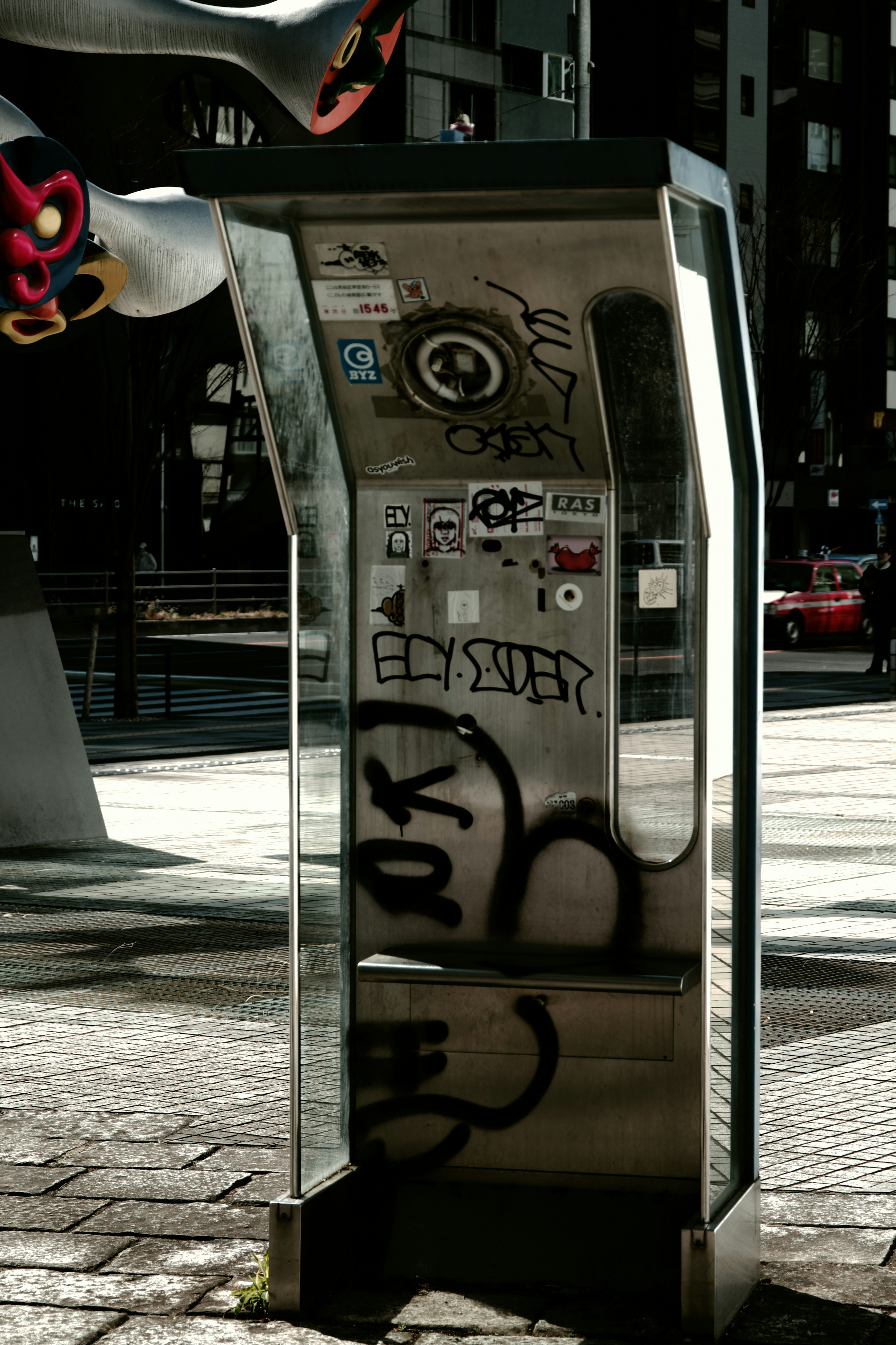 Cabine téléphonique urbaine avec des autocollants et des graffitis montrant un art de rue unique