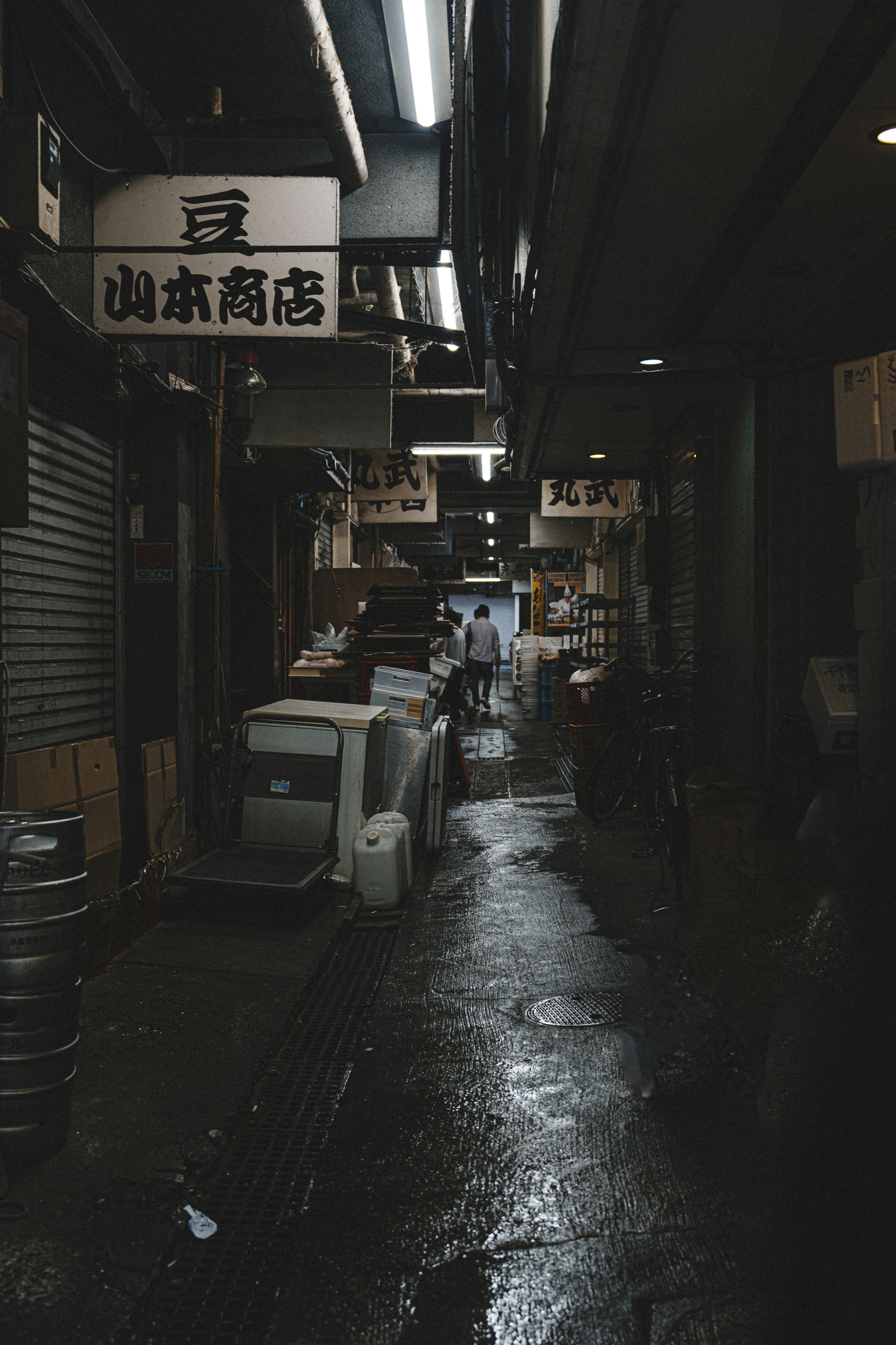 Narrow alley featuring a shop sign and wet pavement