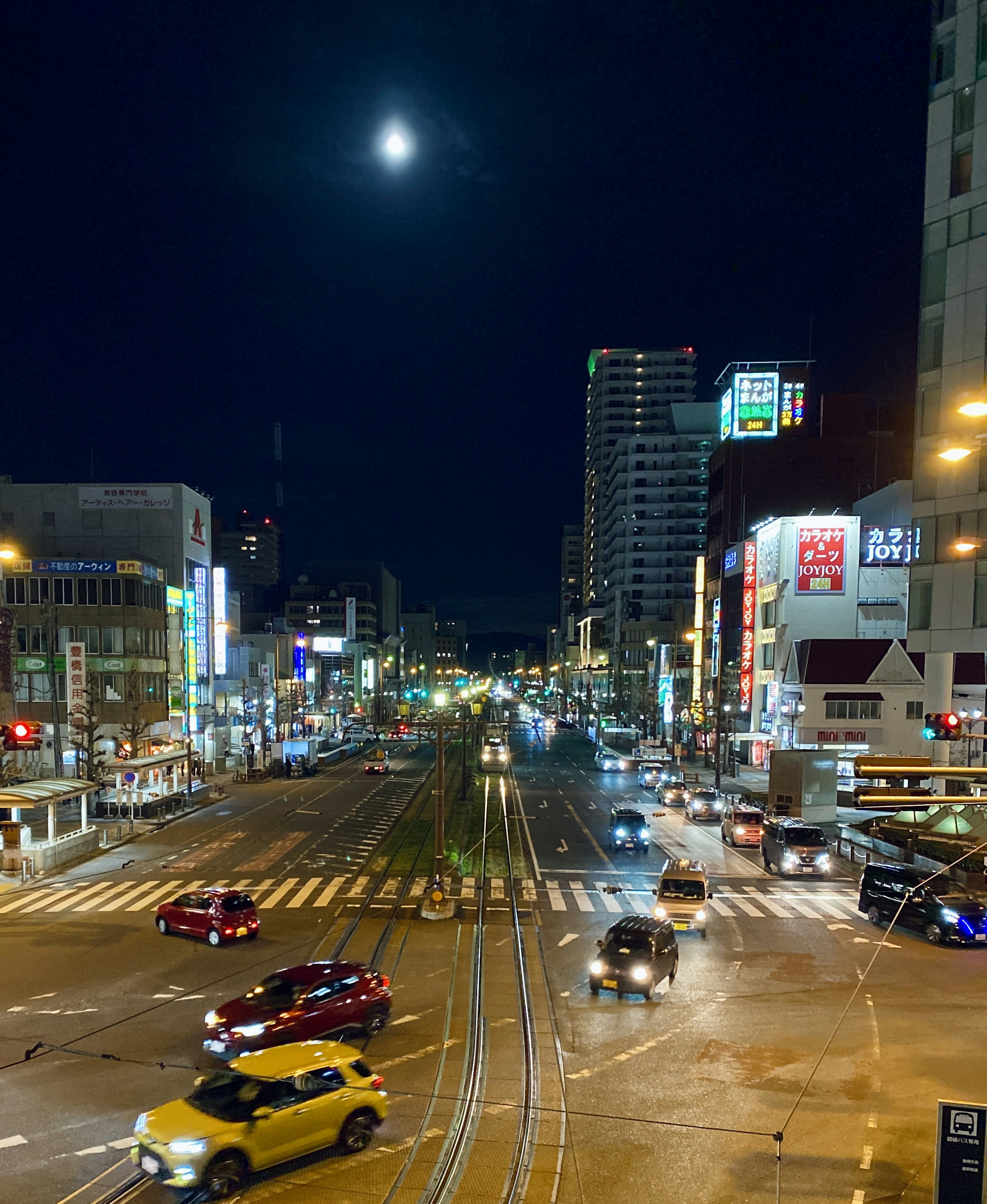 夜の街並みと月明かりの下での交通