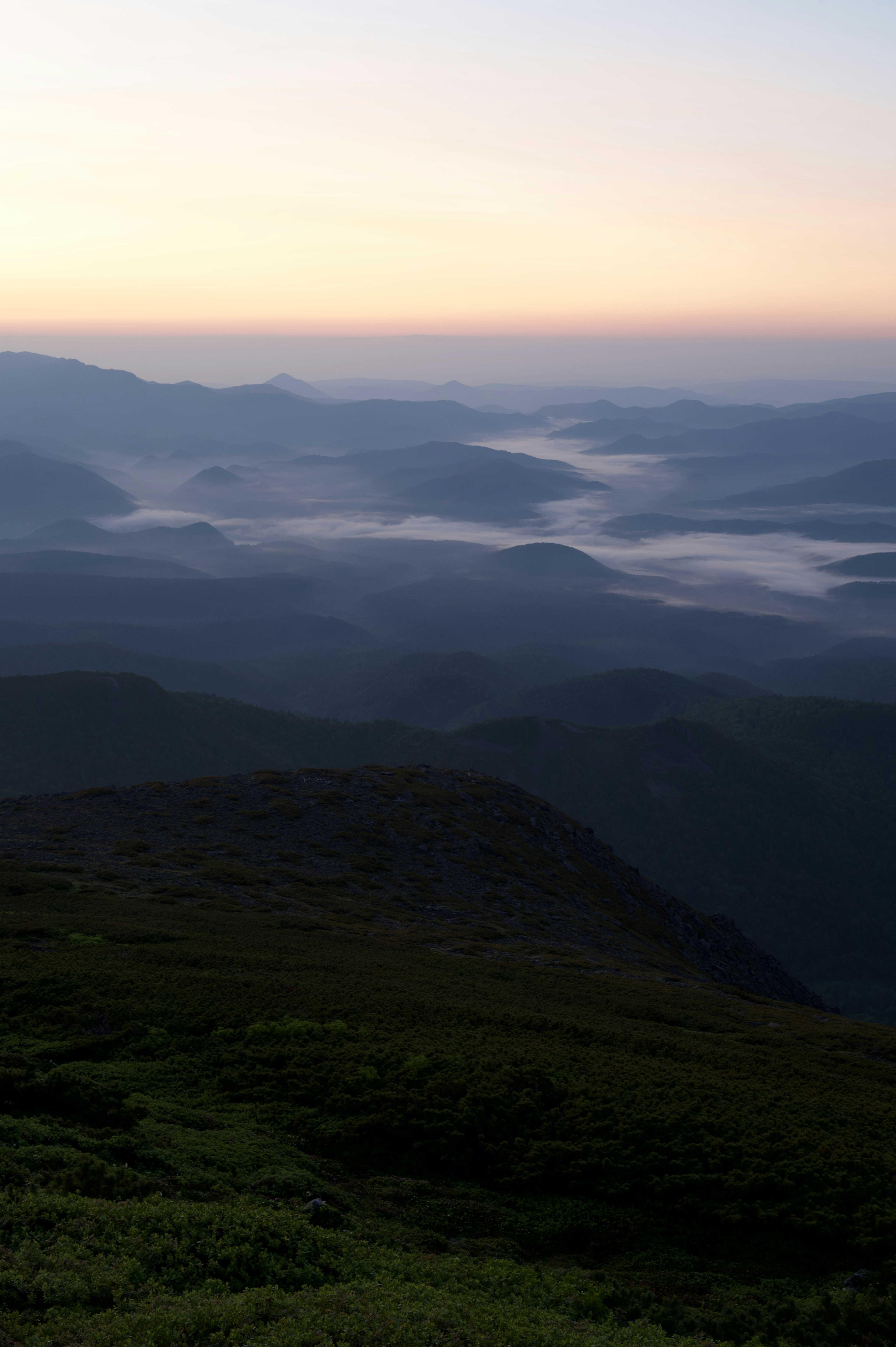 Paisaje montañoso al amanecer con niebla y colores suaves