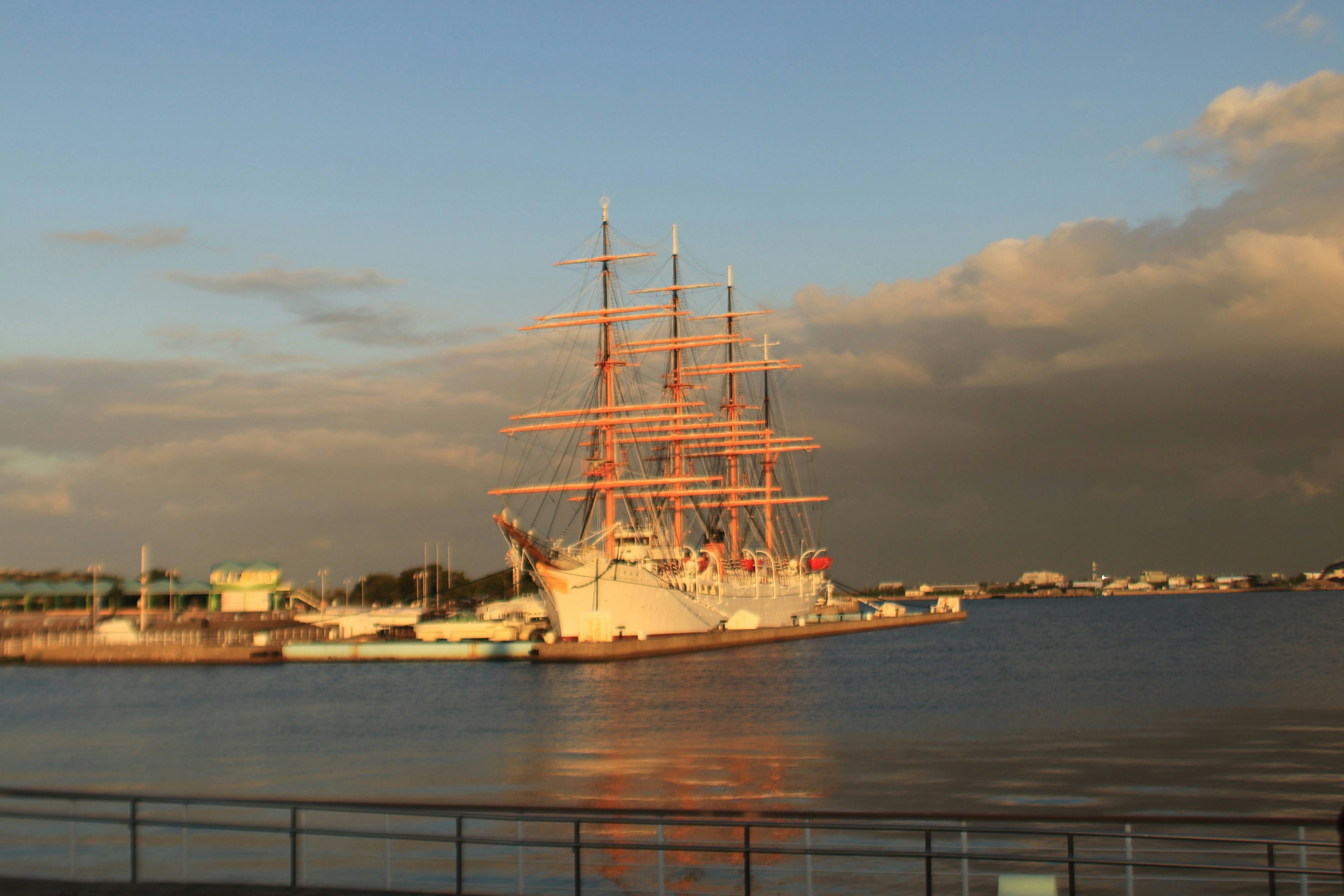 Ein schönes Segelschiff, das im Sonnenuntergang beleuchtet wird, mit Blick auf den Hafen