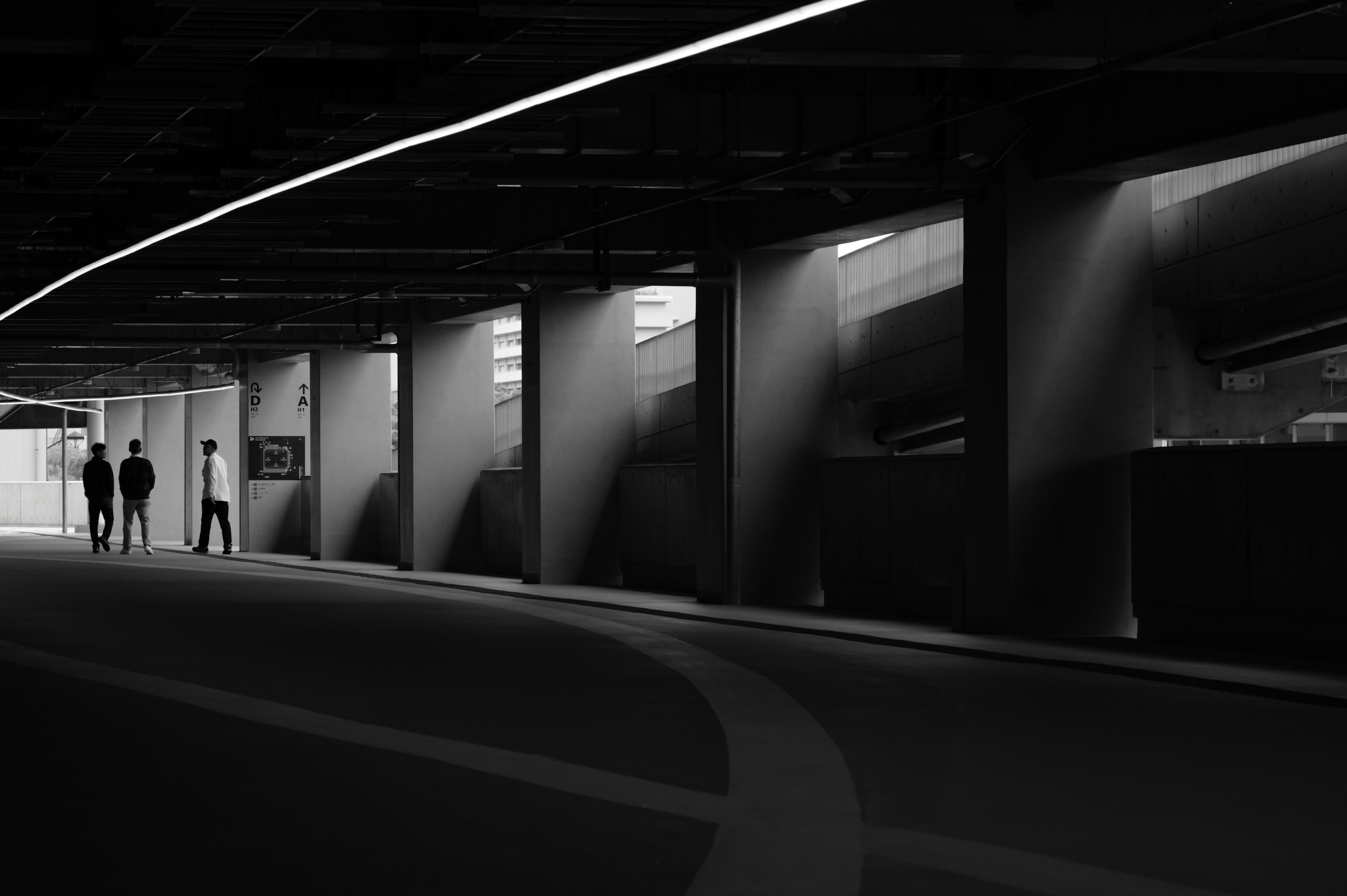 People walking in a dark tunnel with striking light and shadow contrasts