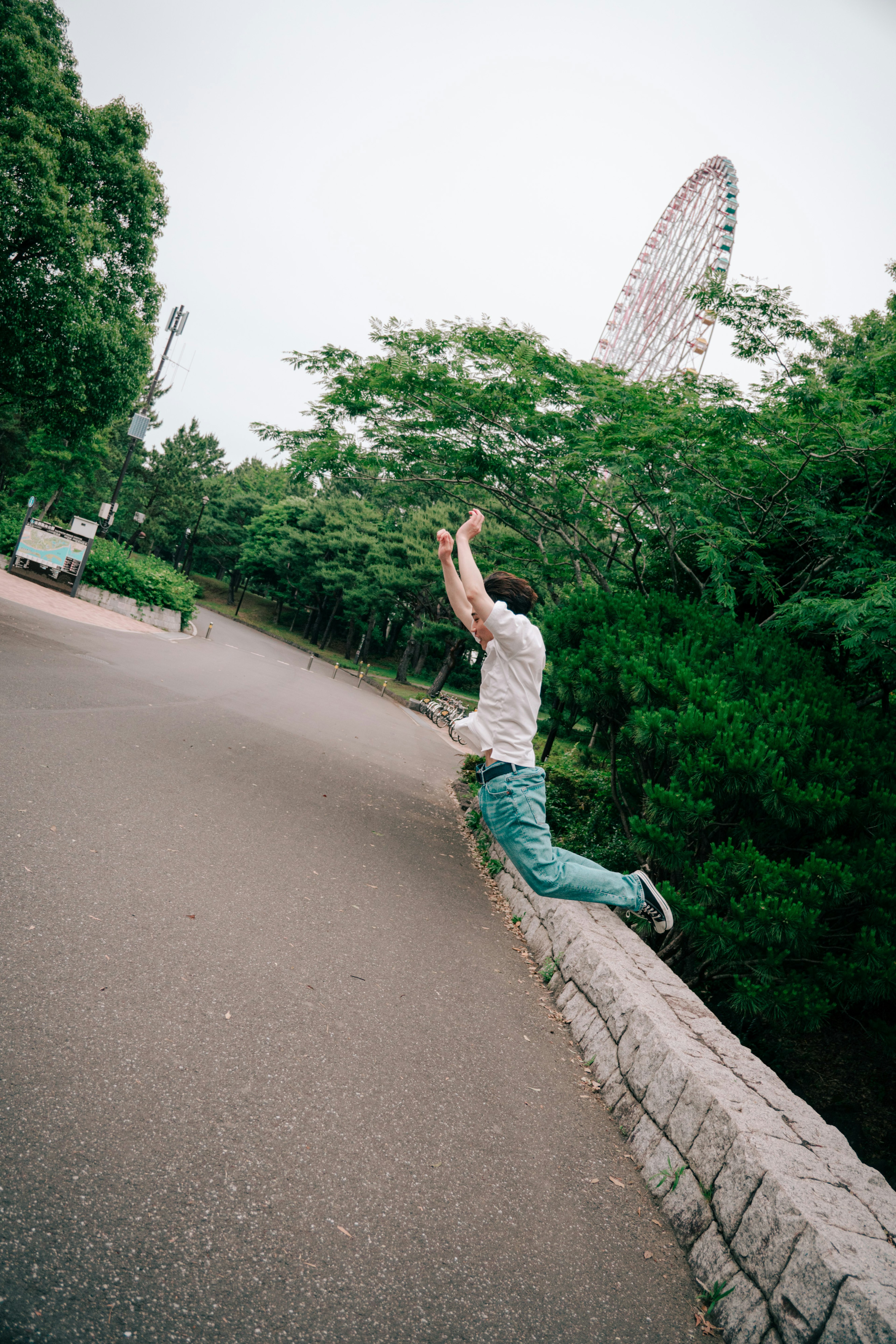 公園で飛び跳ねる男性と緑の木々の風景