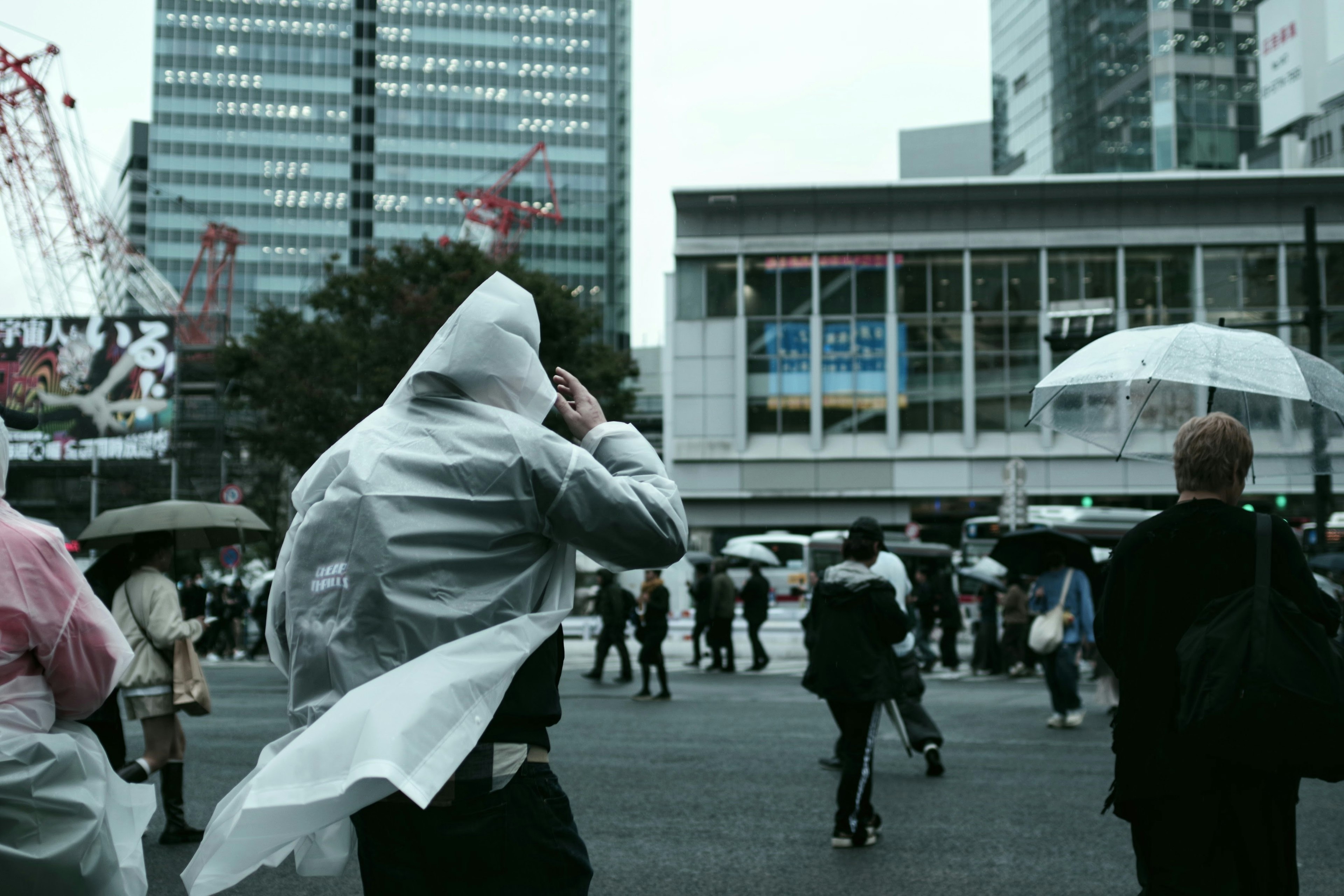 雨の中を歩く人々とビル群が見える都市の風景