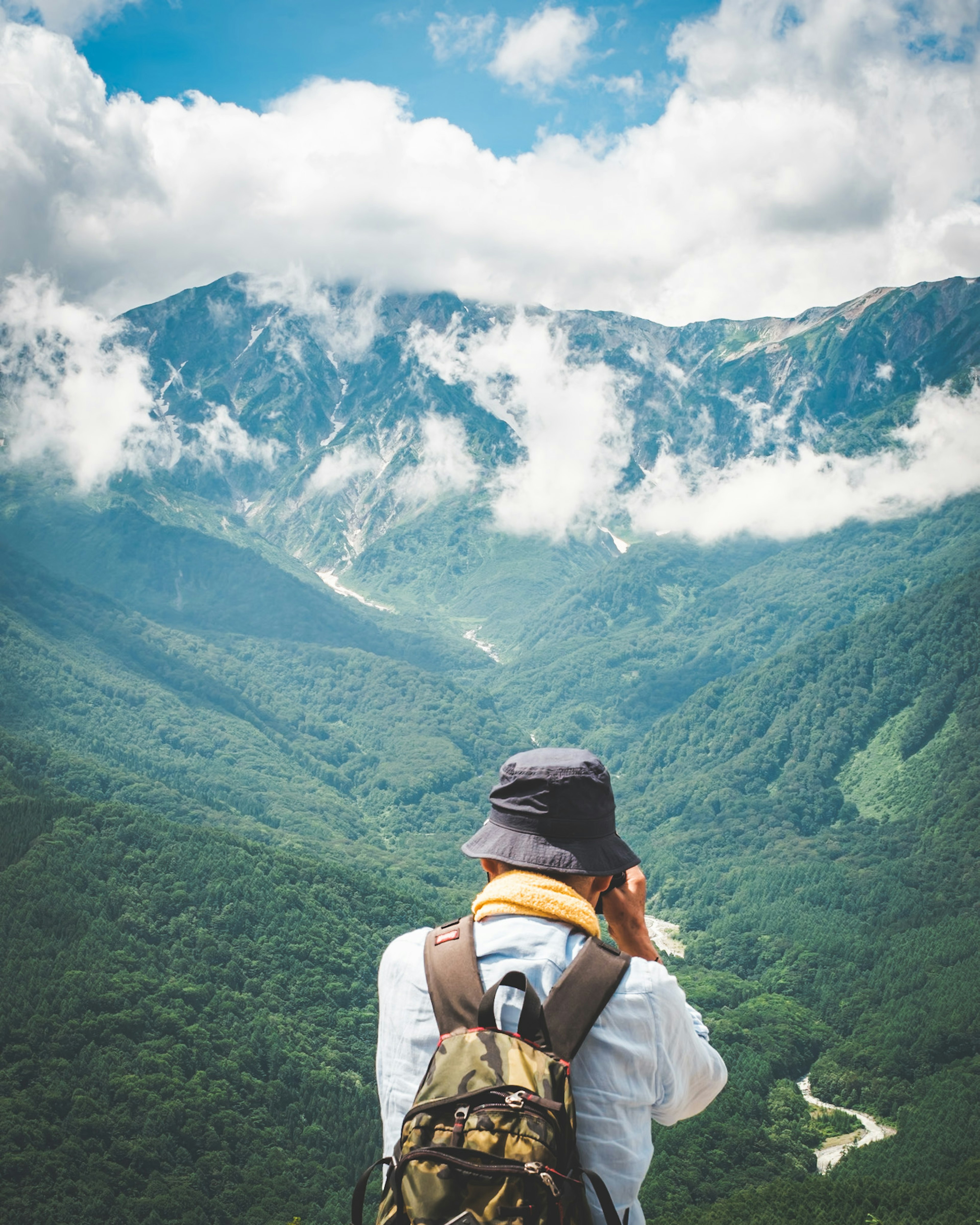 Escursionista che scatta una foto con montagne e nuvole sullo sfondo