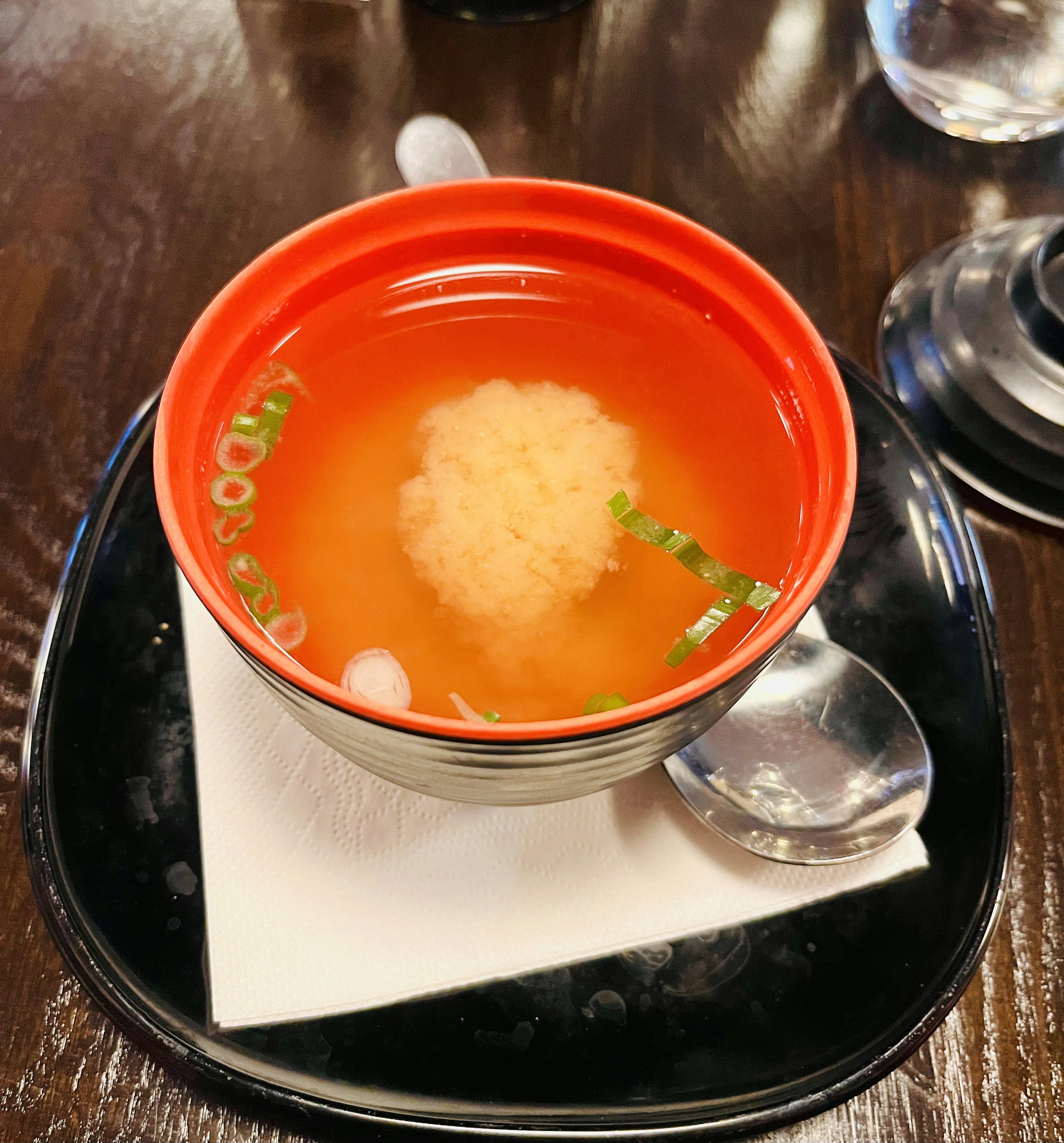 Sopa de miso servida en un tazón rojo con cebollín