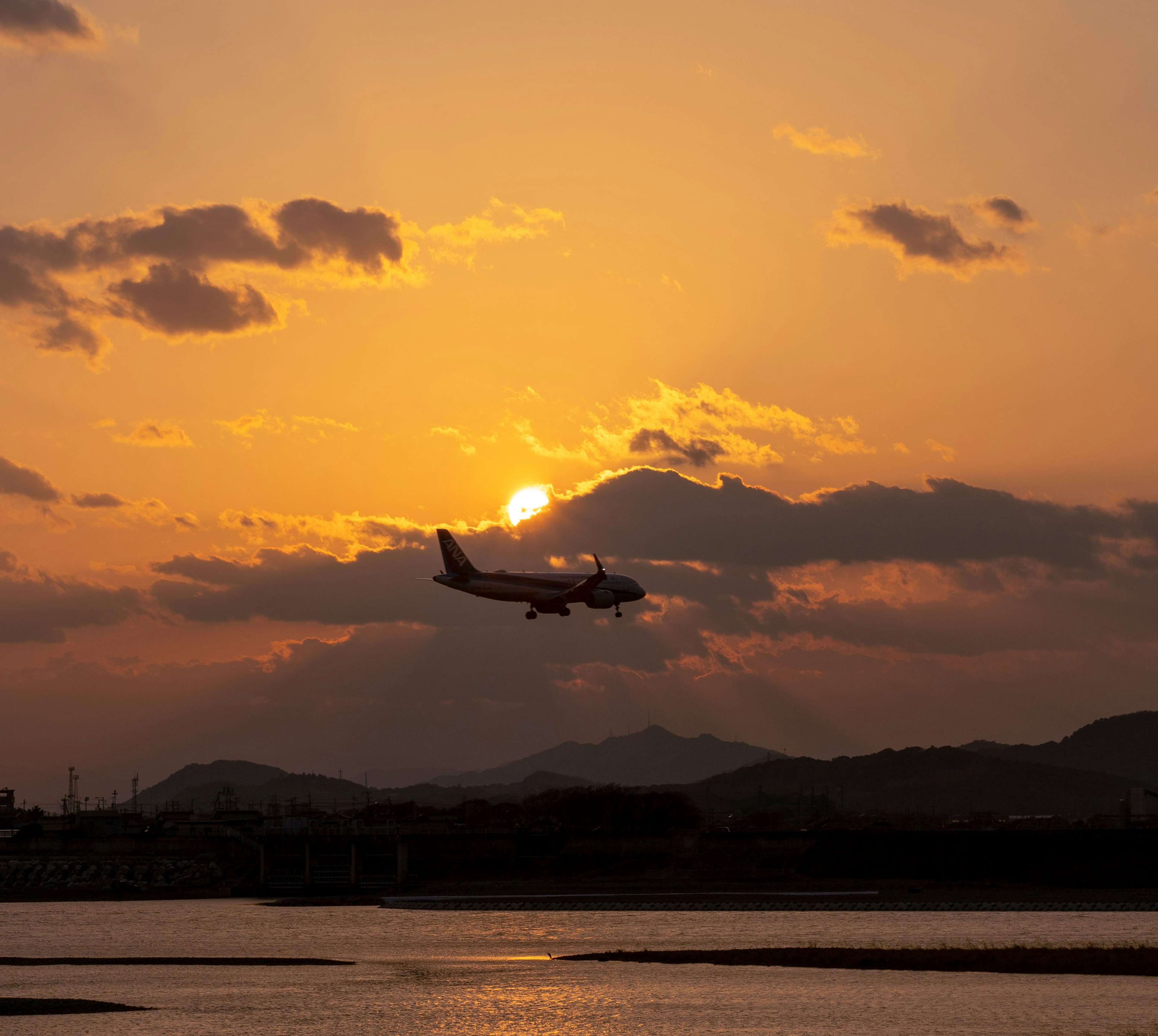 夕日を背景に飛行機が飛んでいる情景