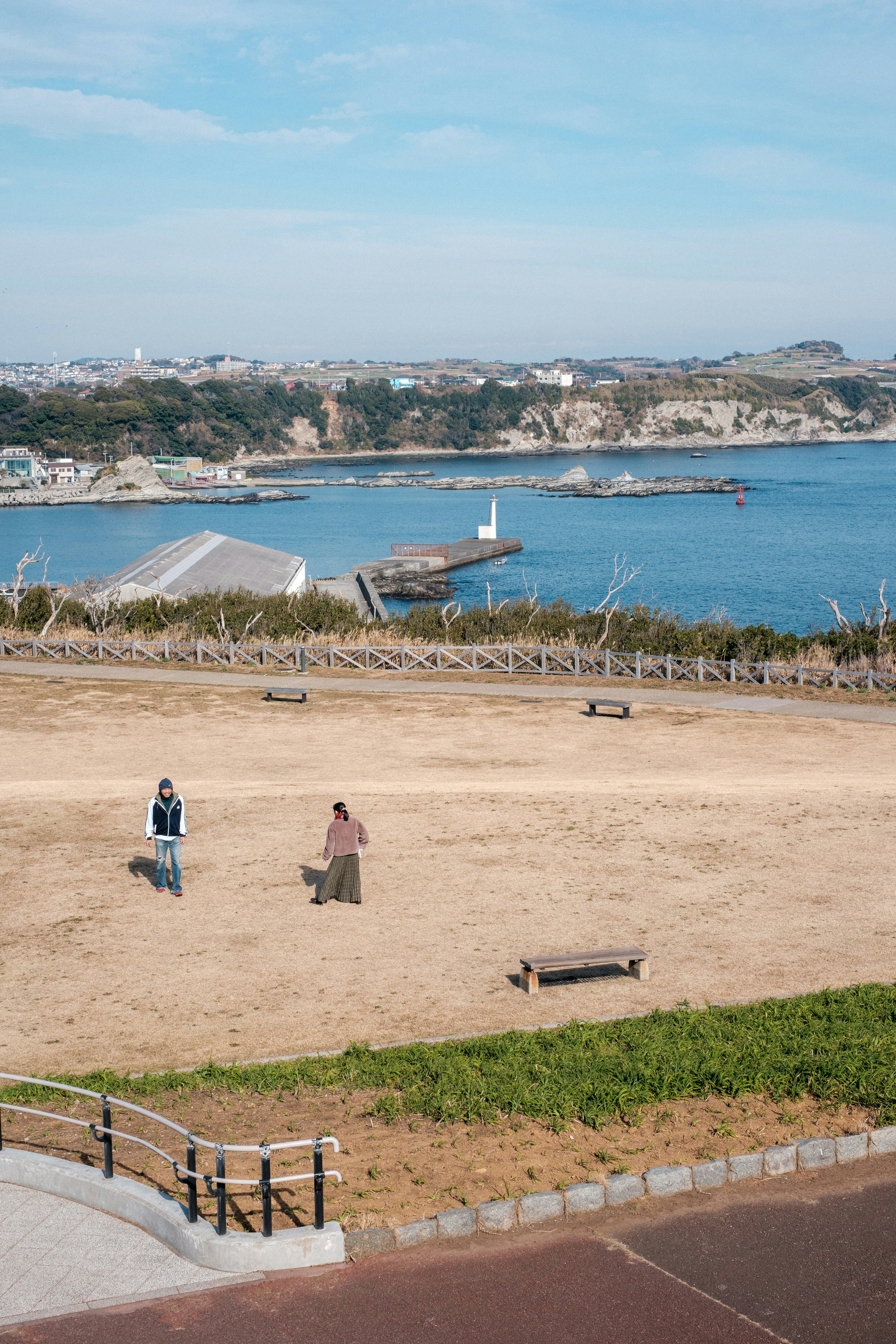 海と公園を背景にした散歩する二人の人物