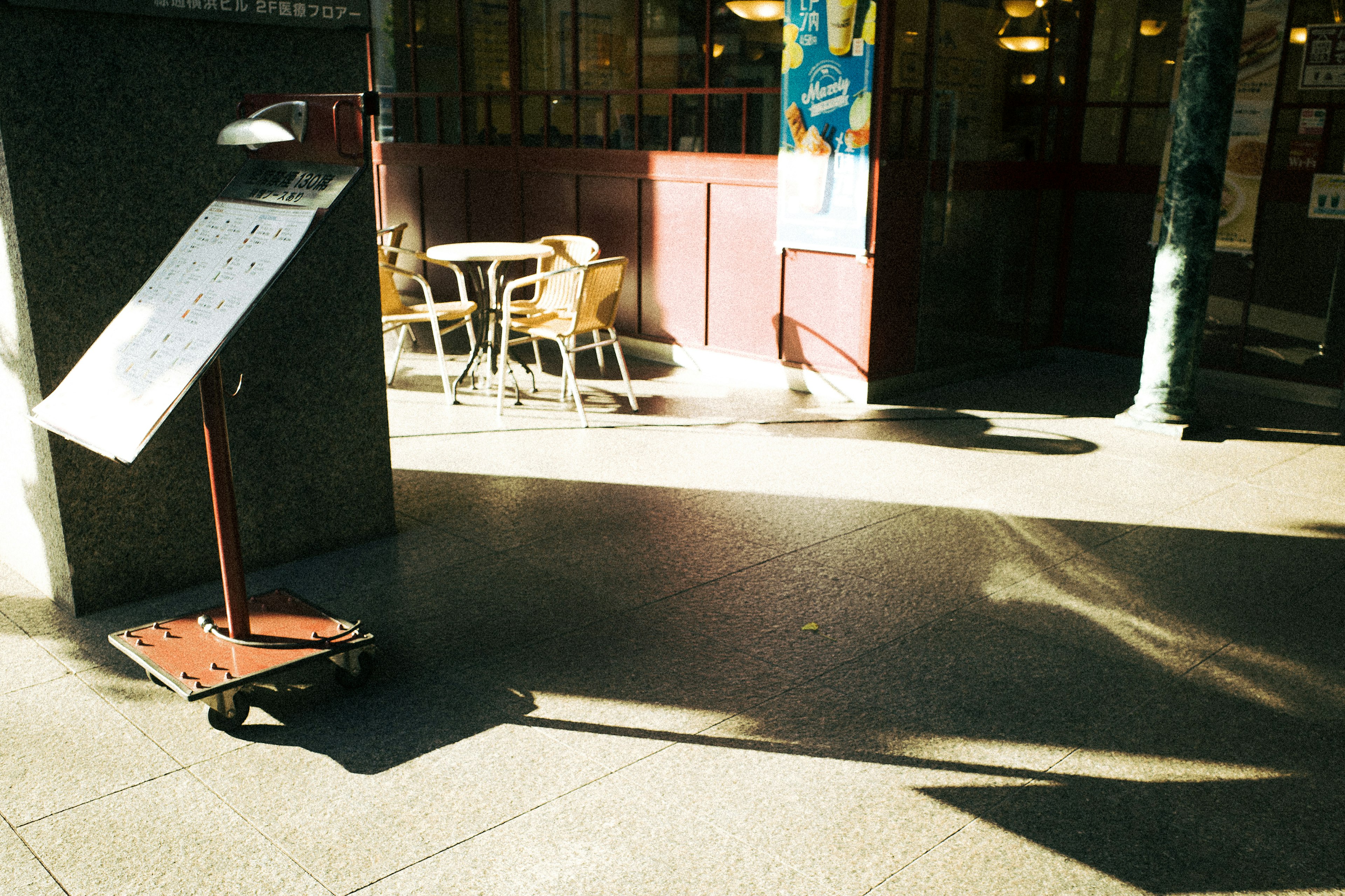 Outdoor café scene featuring a menu board and tables with chairs