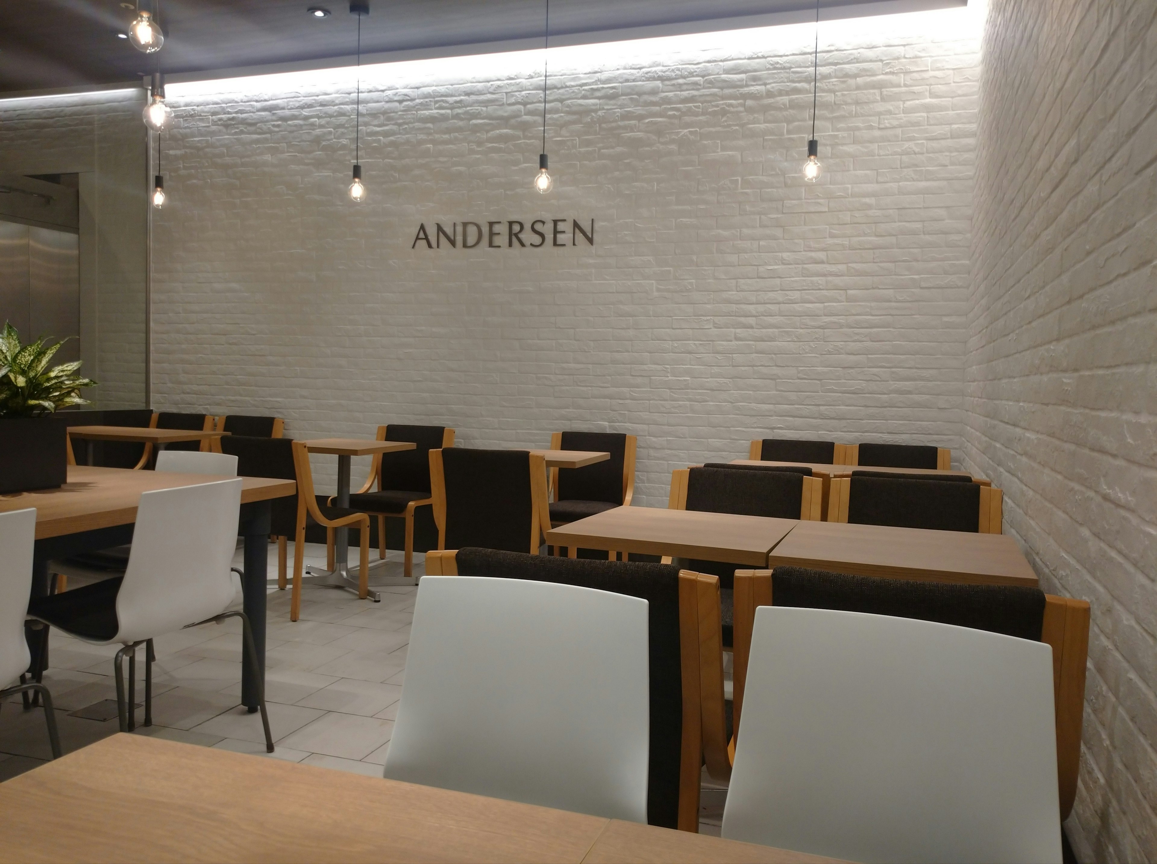 Interior of a cafe featuring white walls and wooden tables