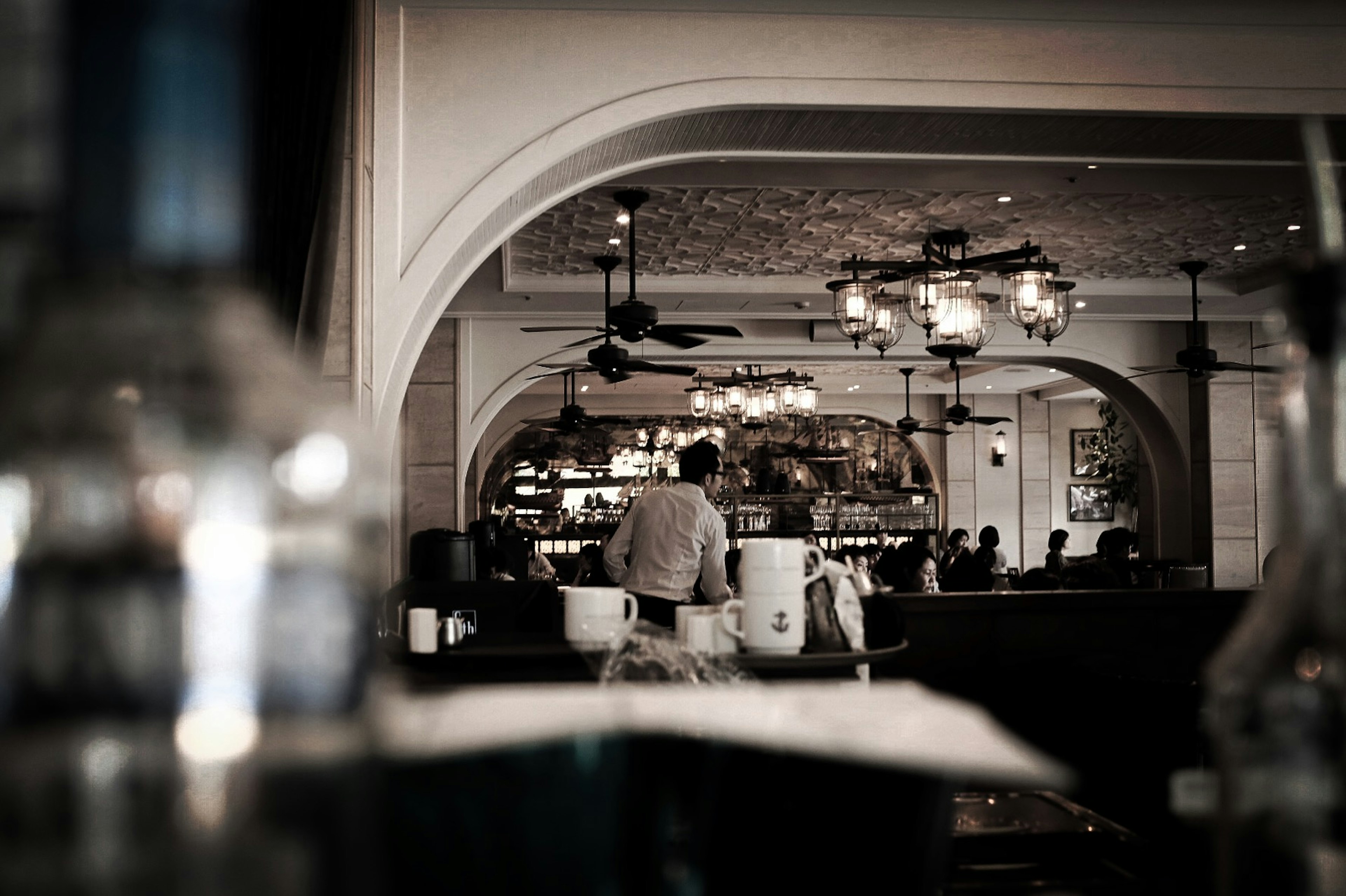 Interior of a restaurant featuring a staff member and decorative ceiling fans