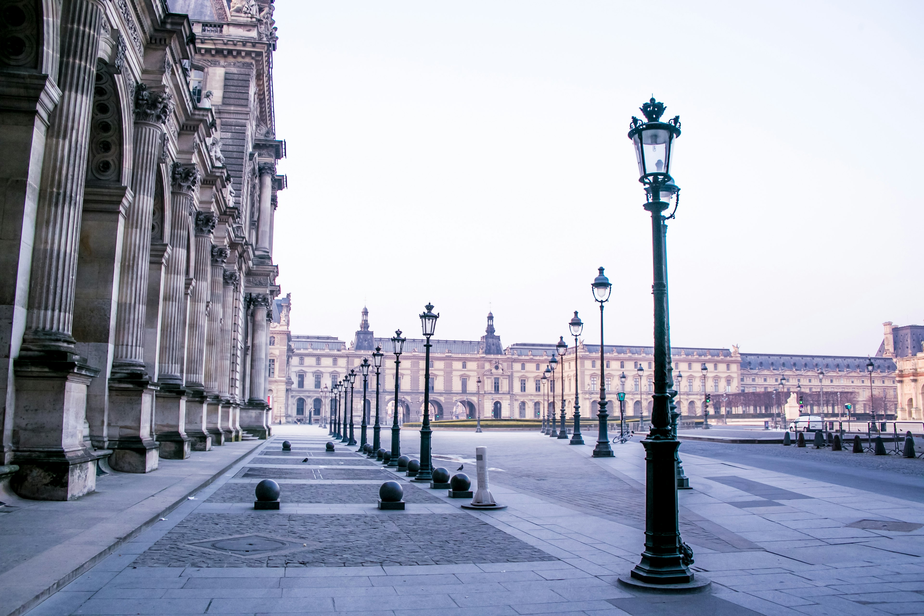 View of the Louvre Museum with street lamps lining the pathway