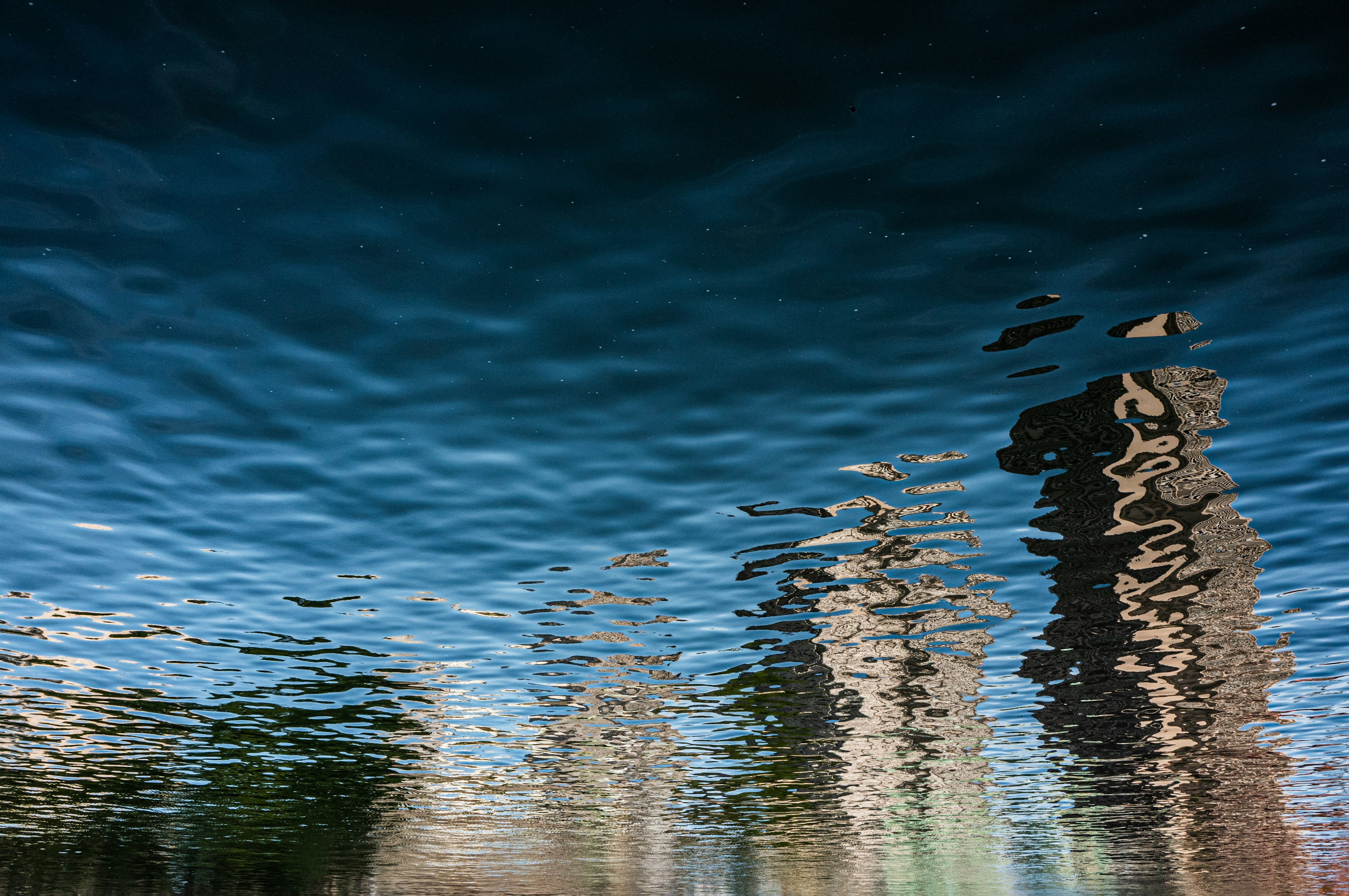 Reflection of skyscrapers on water surface with blue texture