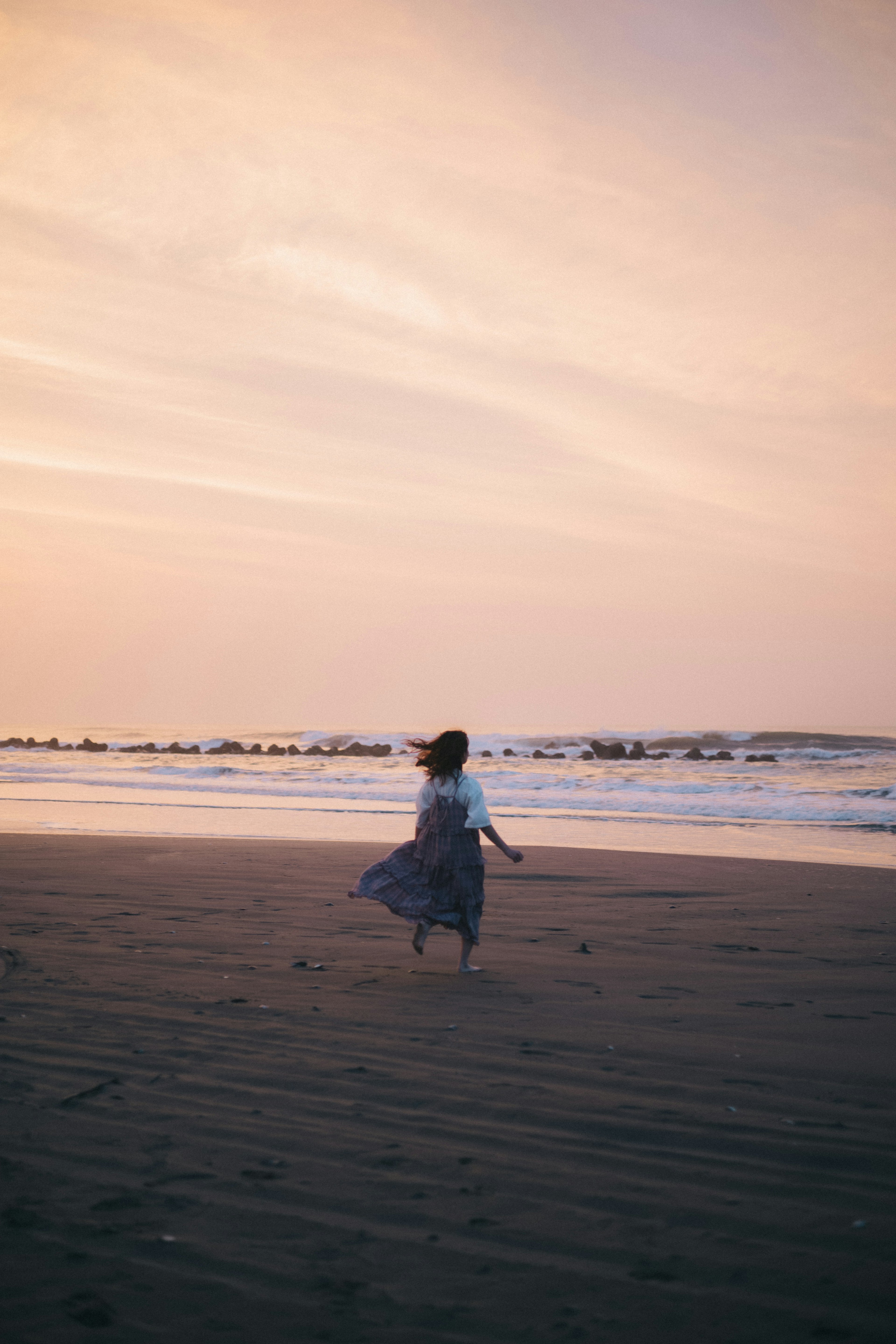 海辺でくるくる回る女性のシルエットと美しい夕焼け