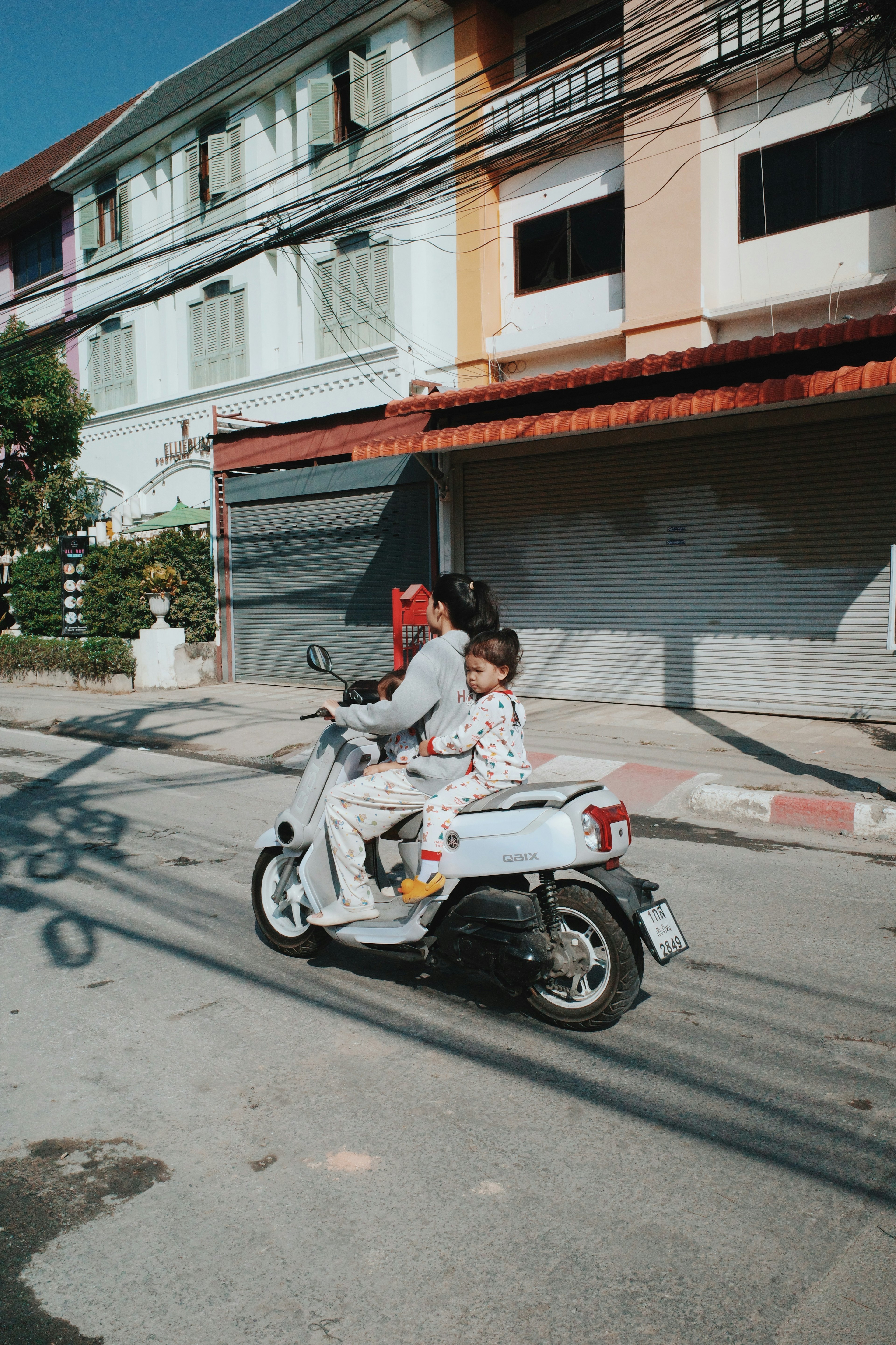 Parent and child riding a white scooter on a street