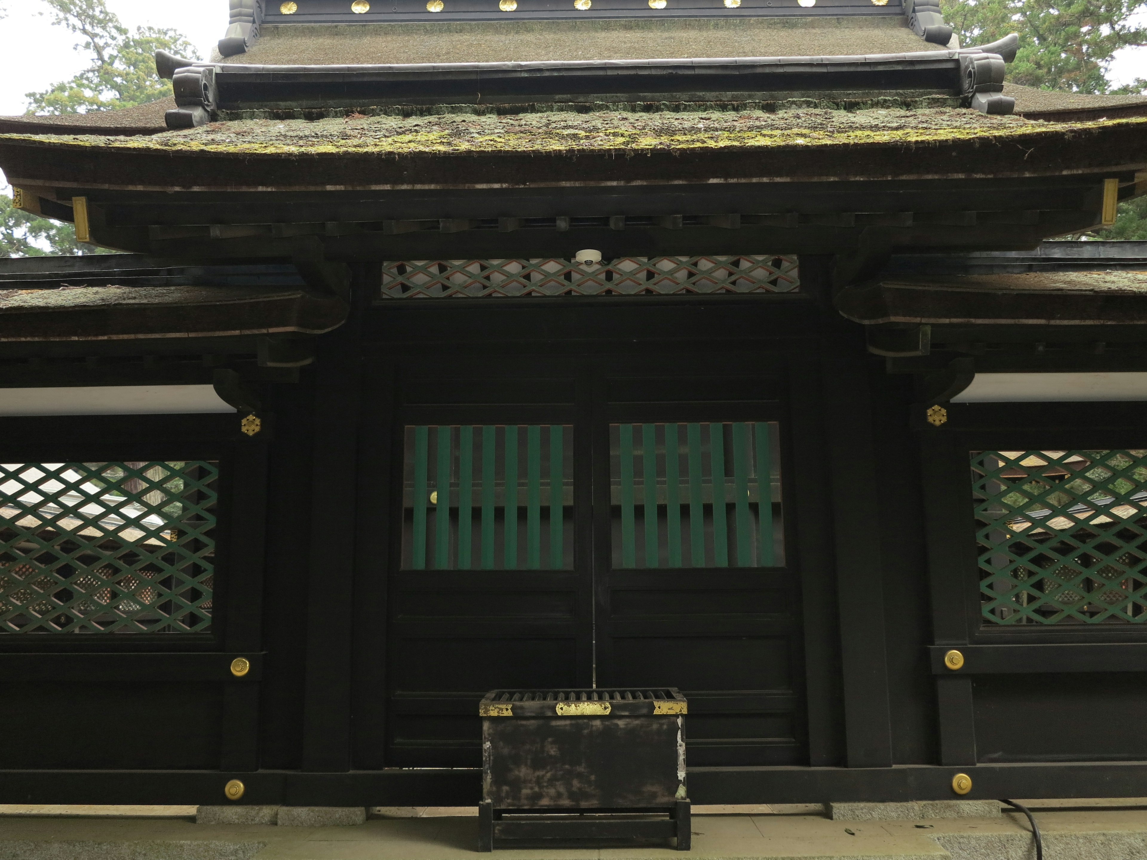 Bâtiment japonais traditionnel avec une porte en bois noir et des fenêtres à treillis vertes