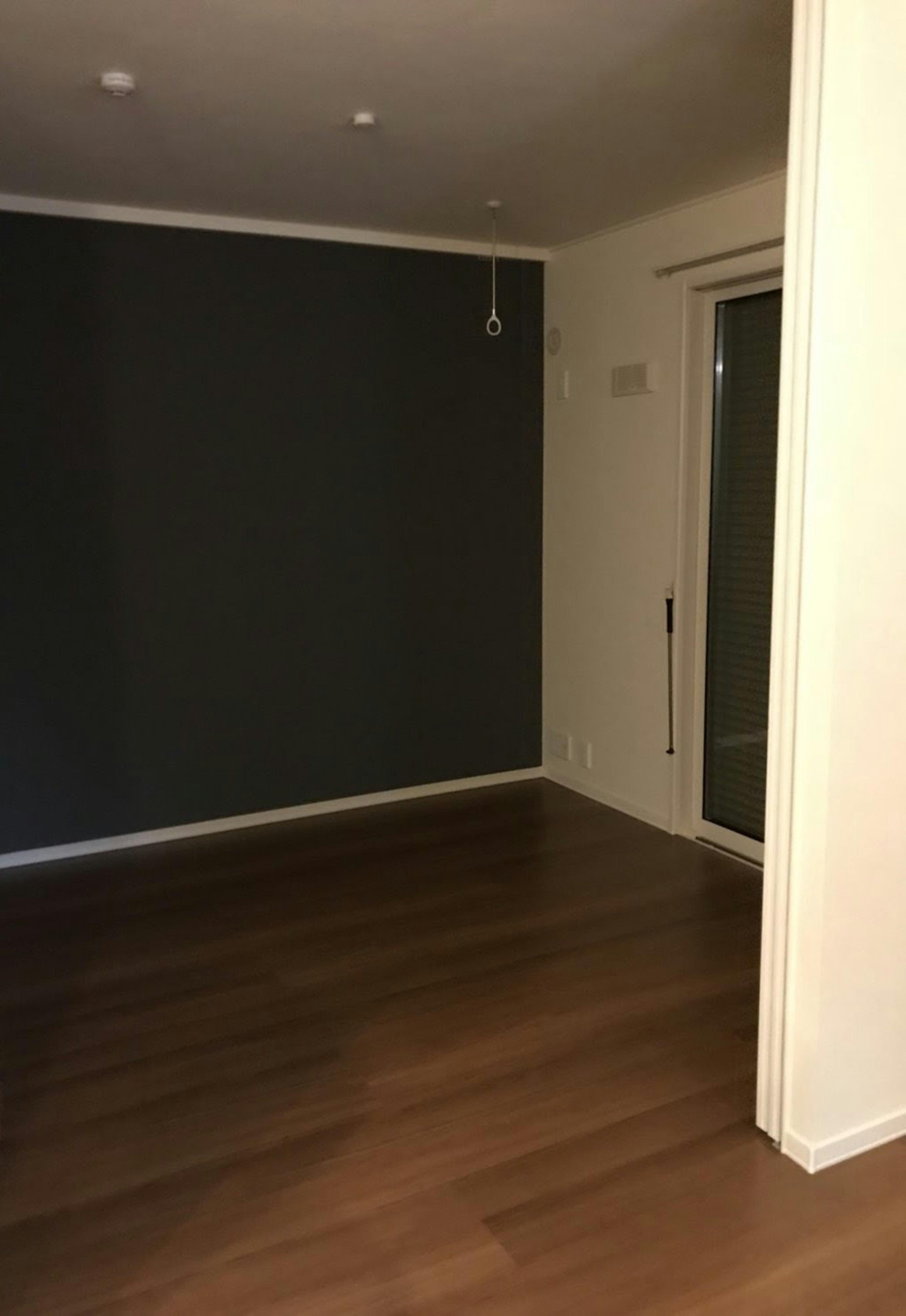 Simple interior space with dark gray wall wooden floor and light from window