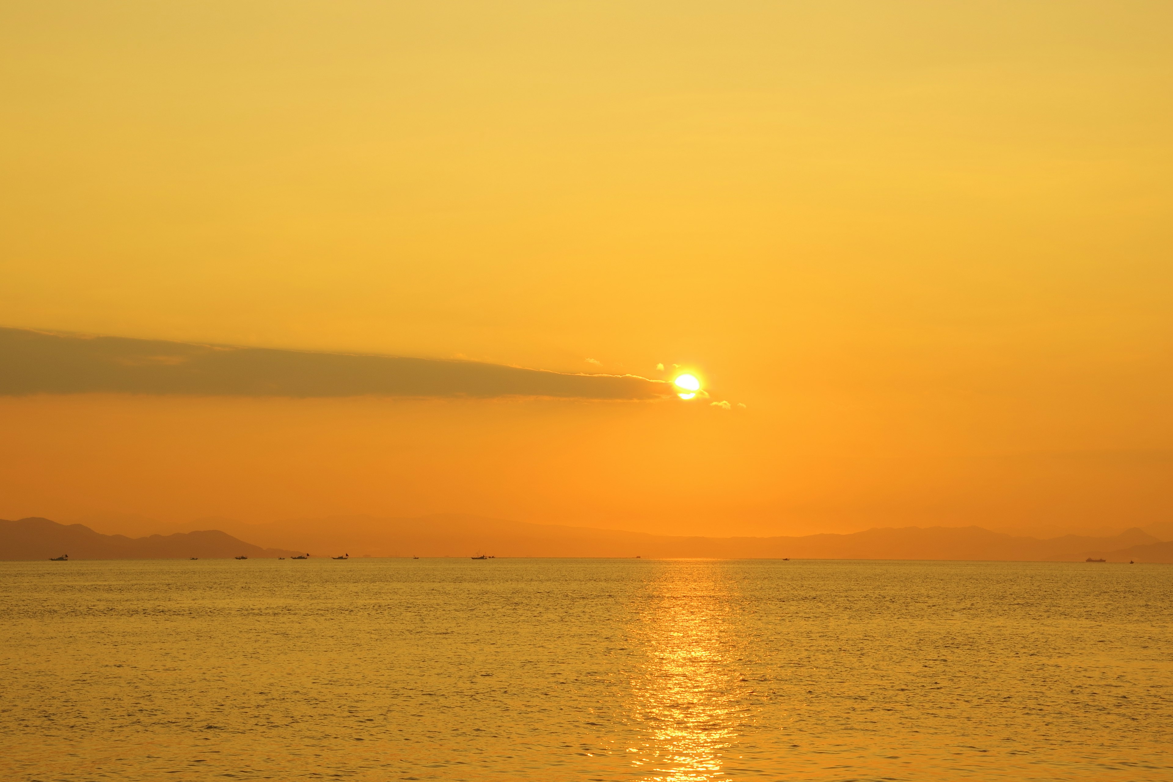 Atardecer sobre el océano con cielo naranja y aguas tranquilas