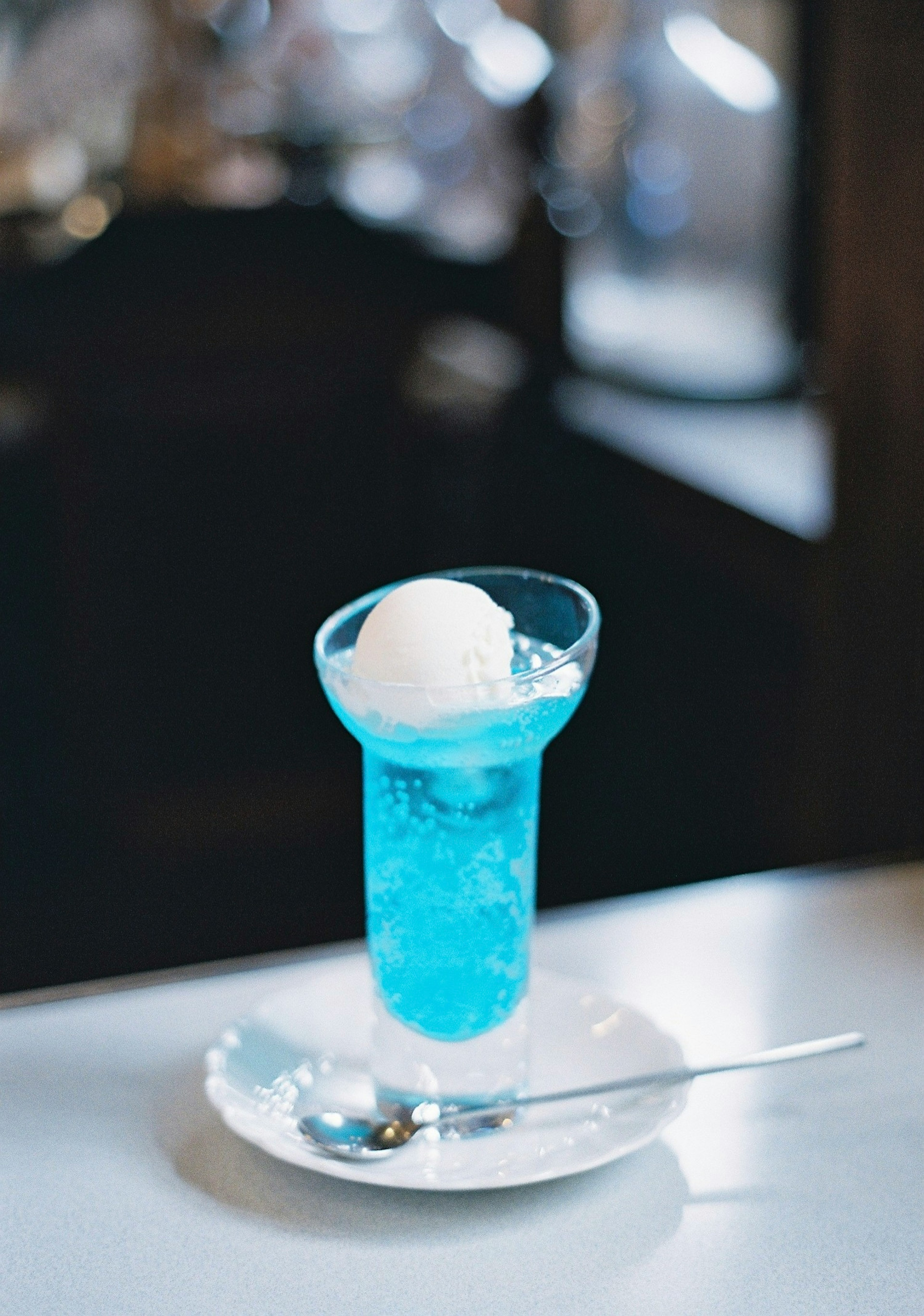 Blue drink topped with ice cream in a glass