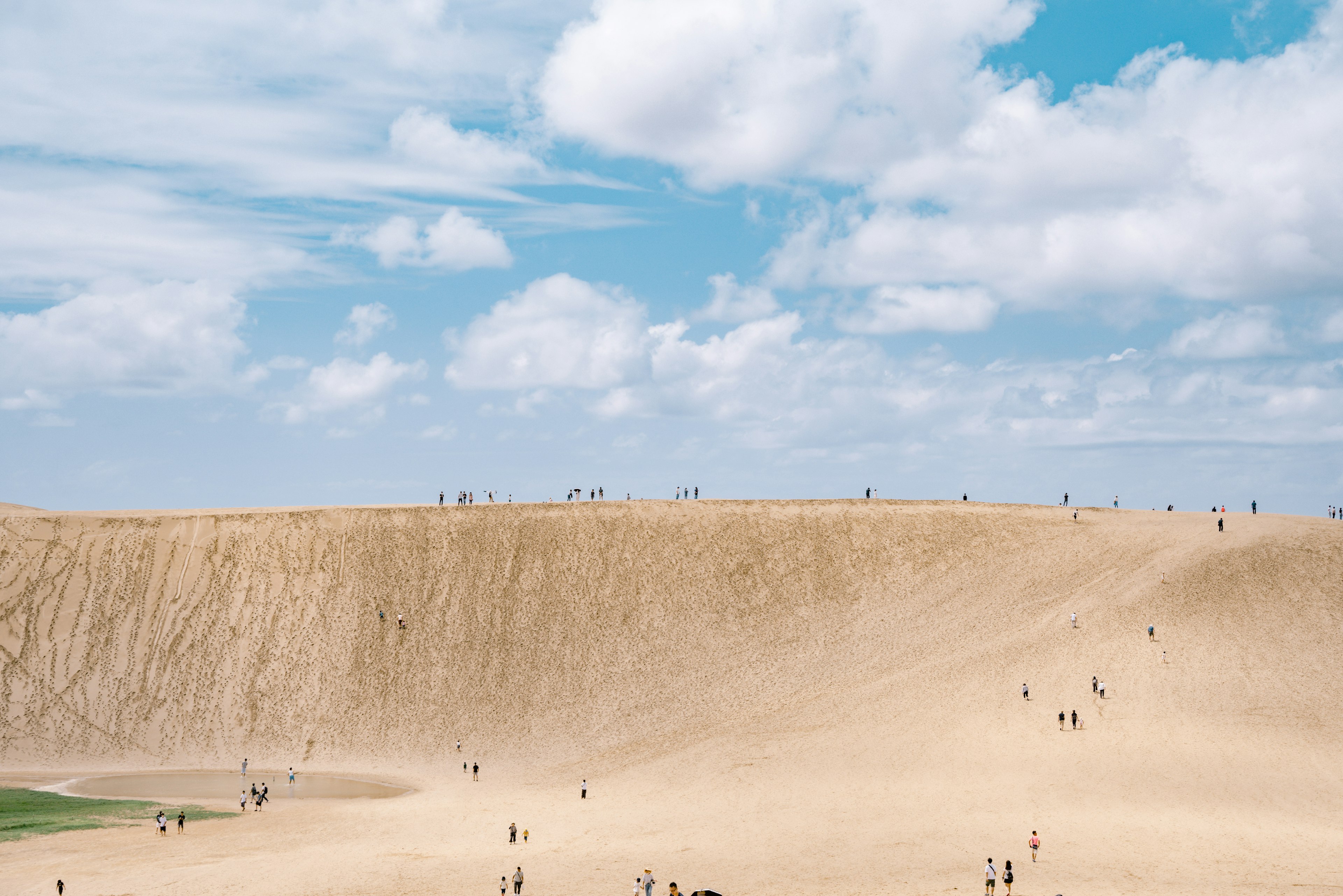 Menschen, die auf einer Sanddüne unter einem blauen Himmel gehen