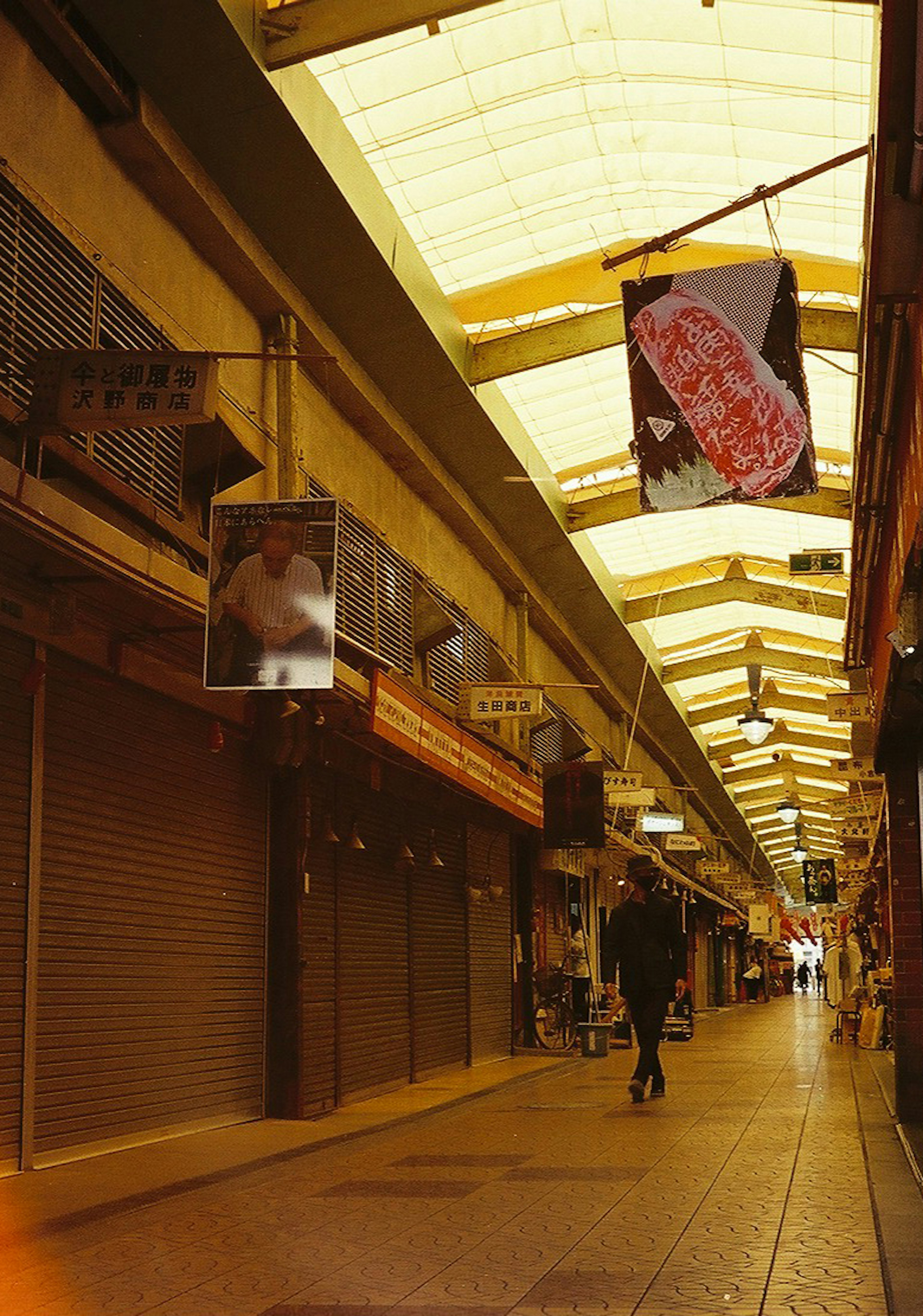 人が歩いている商店街の静かな通路 下にシャッターが下りている店が並ぶ