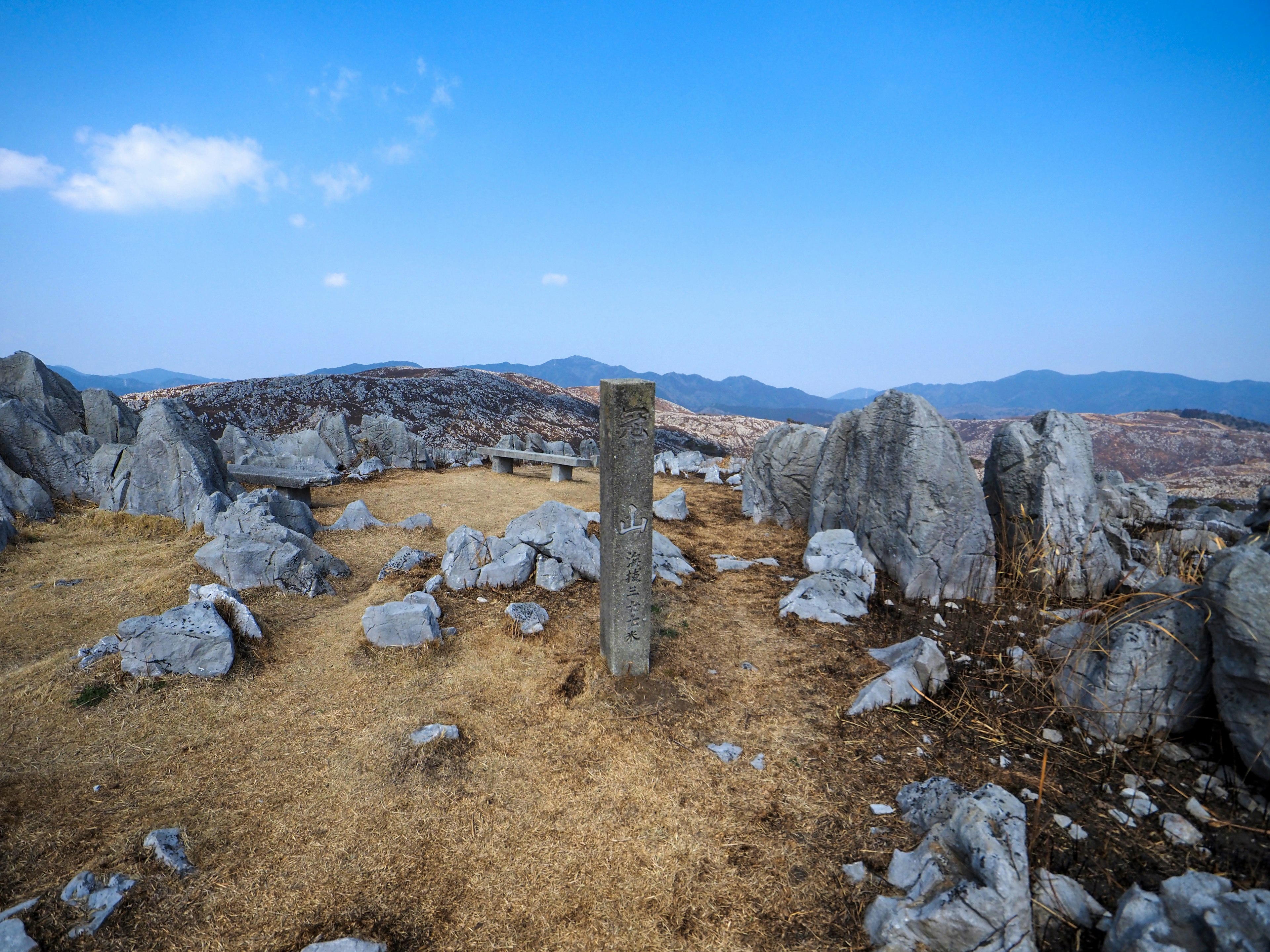 Stone monument standing in a rocky landscape with distant hills