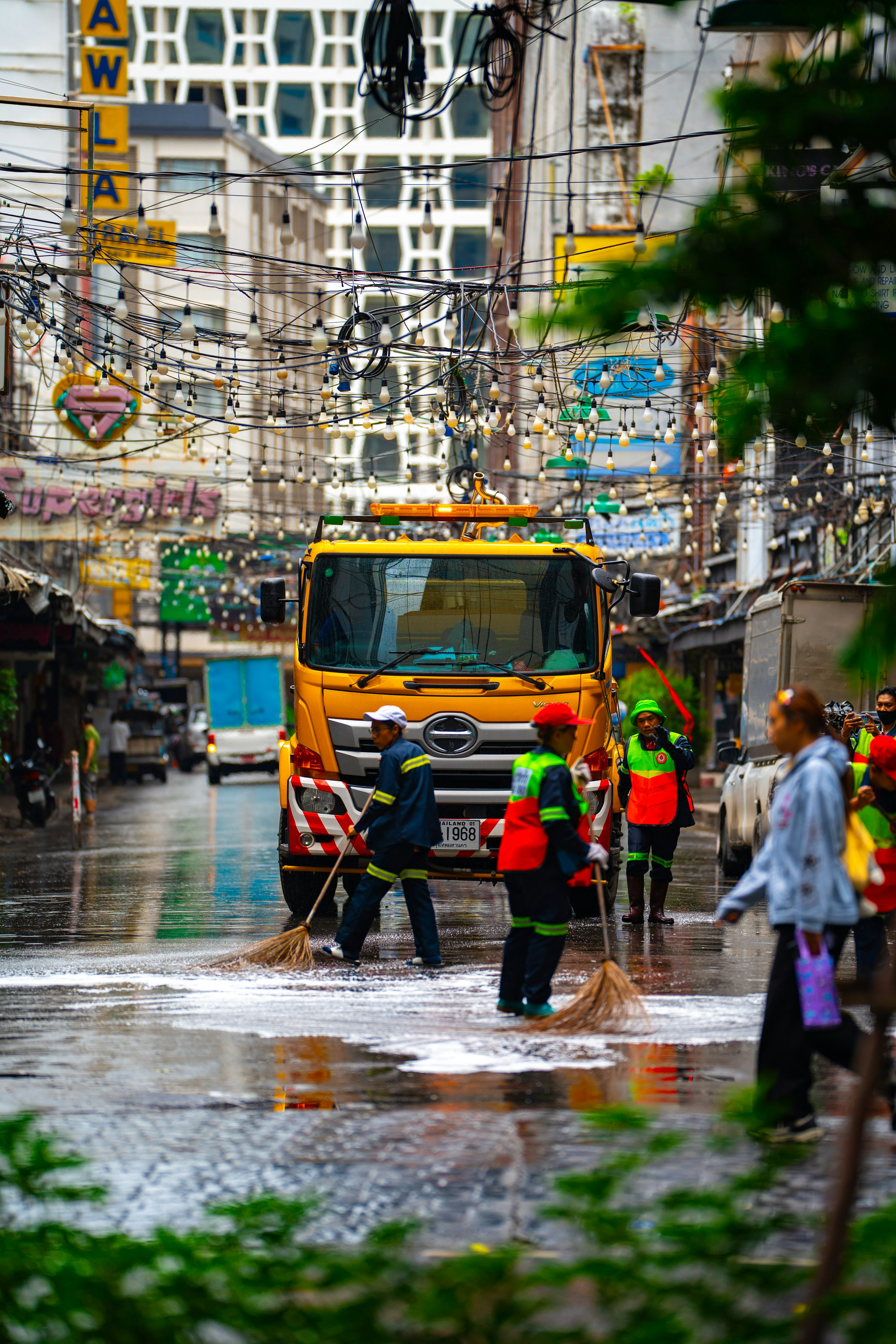 Workers cleaning a wet street with a truck in the background