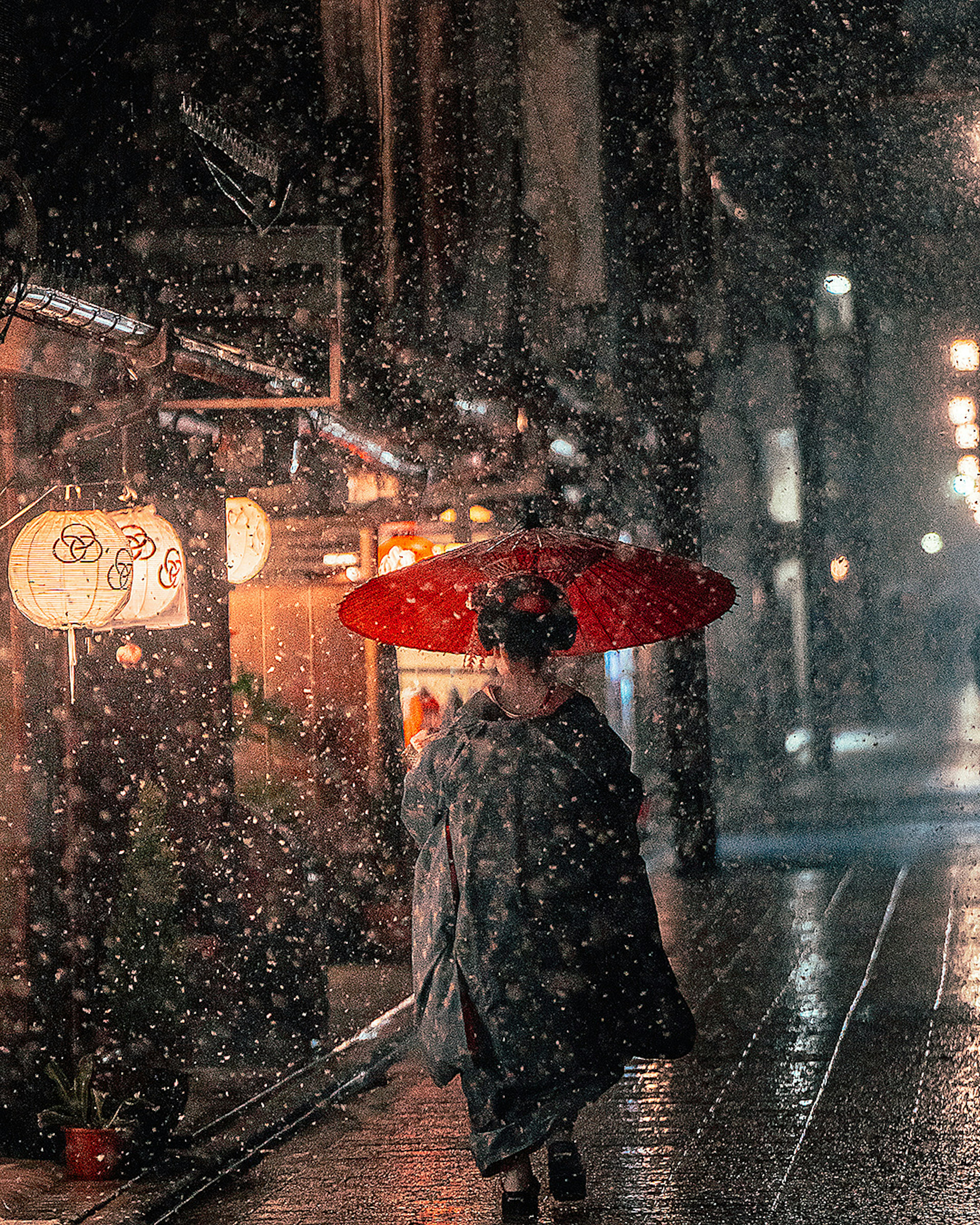 Una mujer caminando bajo la lluvia con un paraguas rojo en un entorno urbano