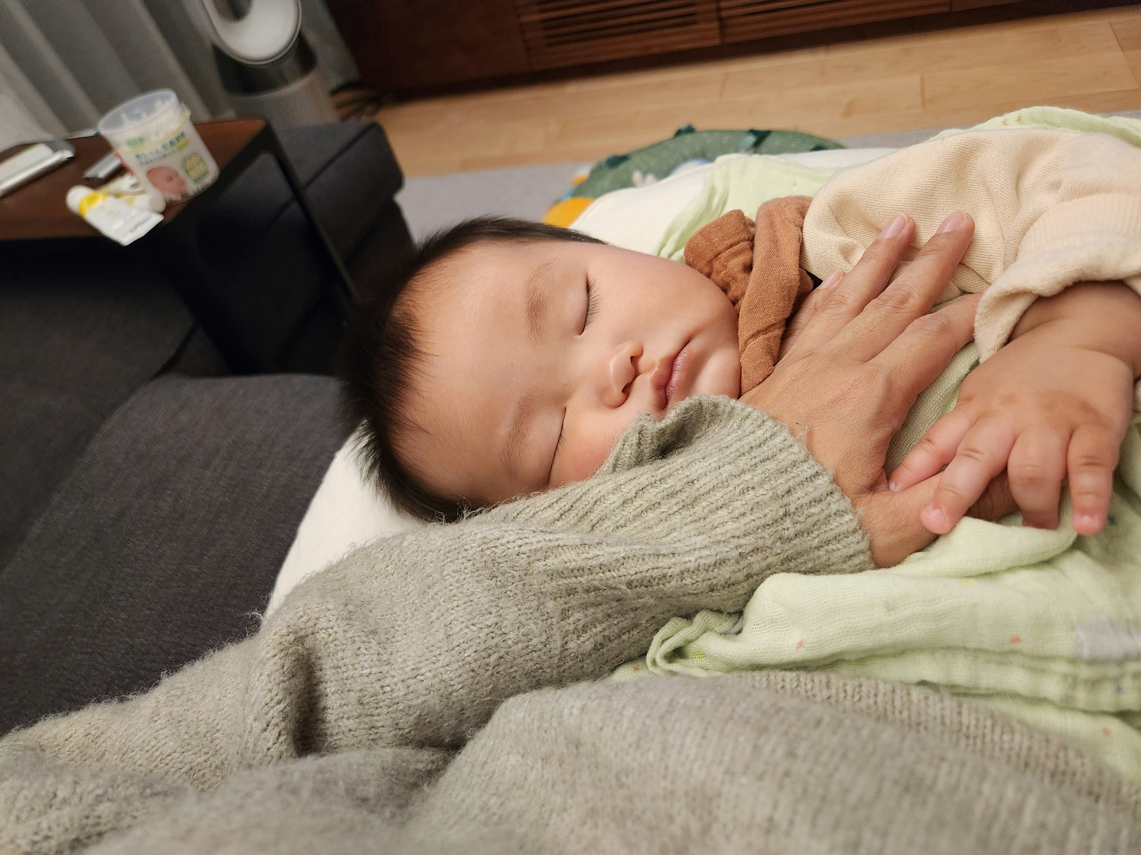 A sleeping baby cradled in gentle hands cozy setting with soft textures