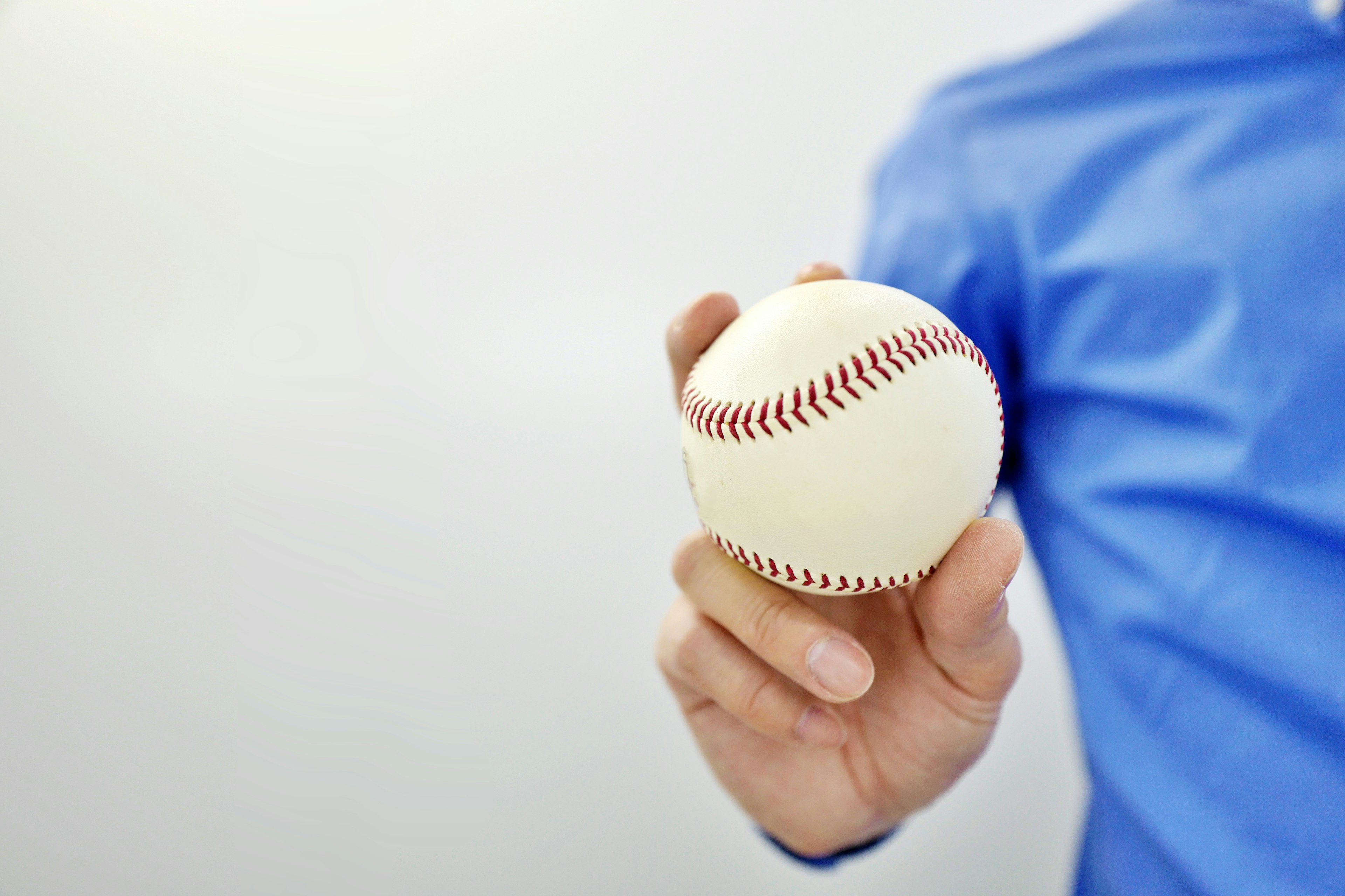 Hombre con camisa azul sosteniendo una pelota de béisbol