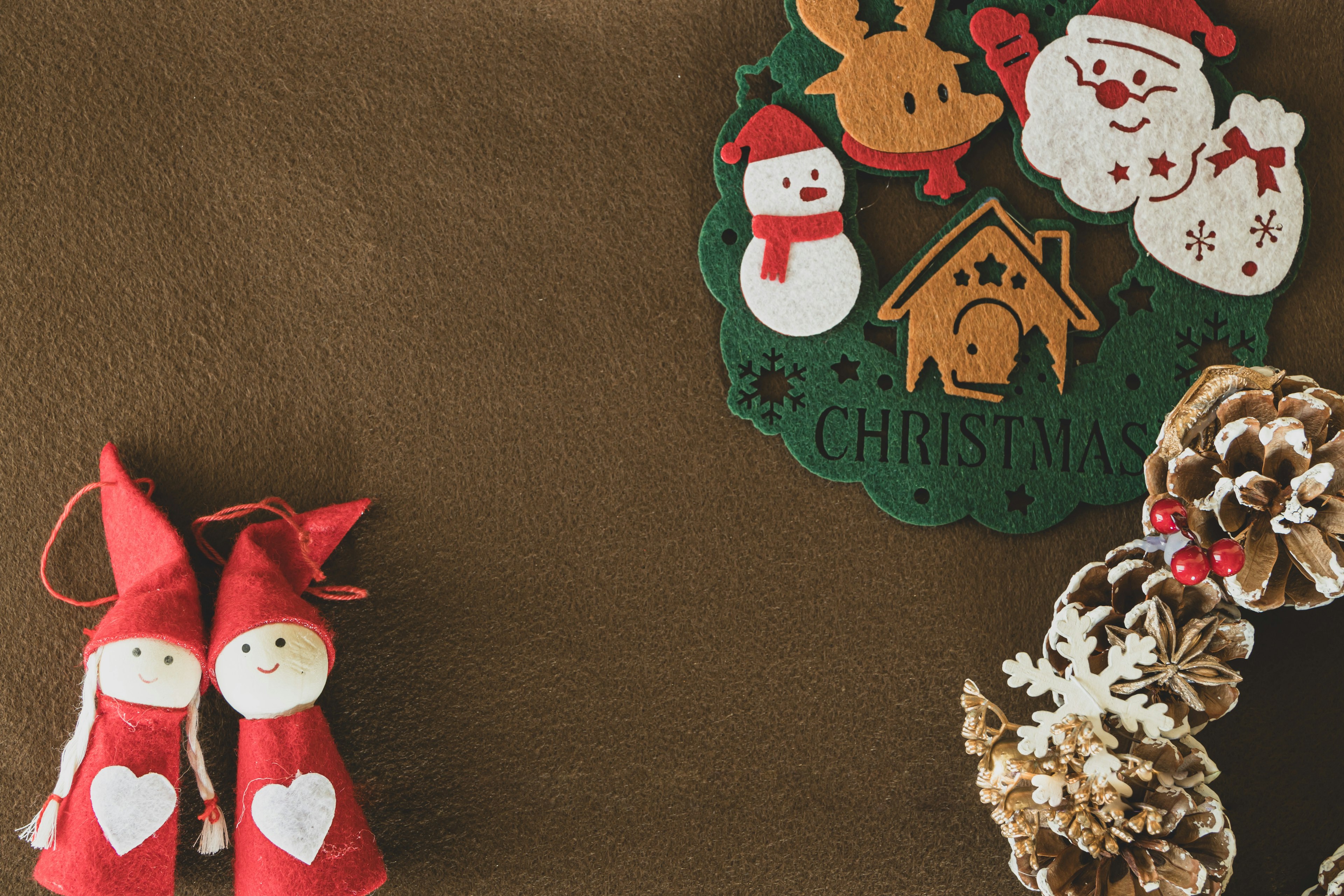 Christmas decorations featuring red-dressed dolls and pine cone ornaments on a brown background