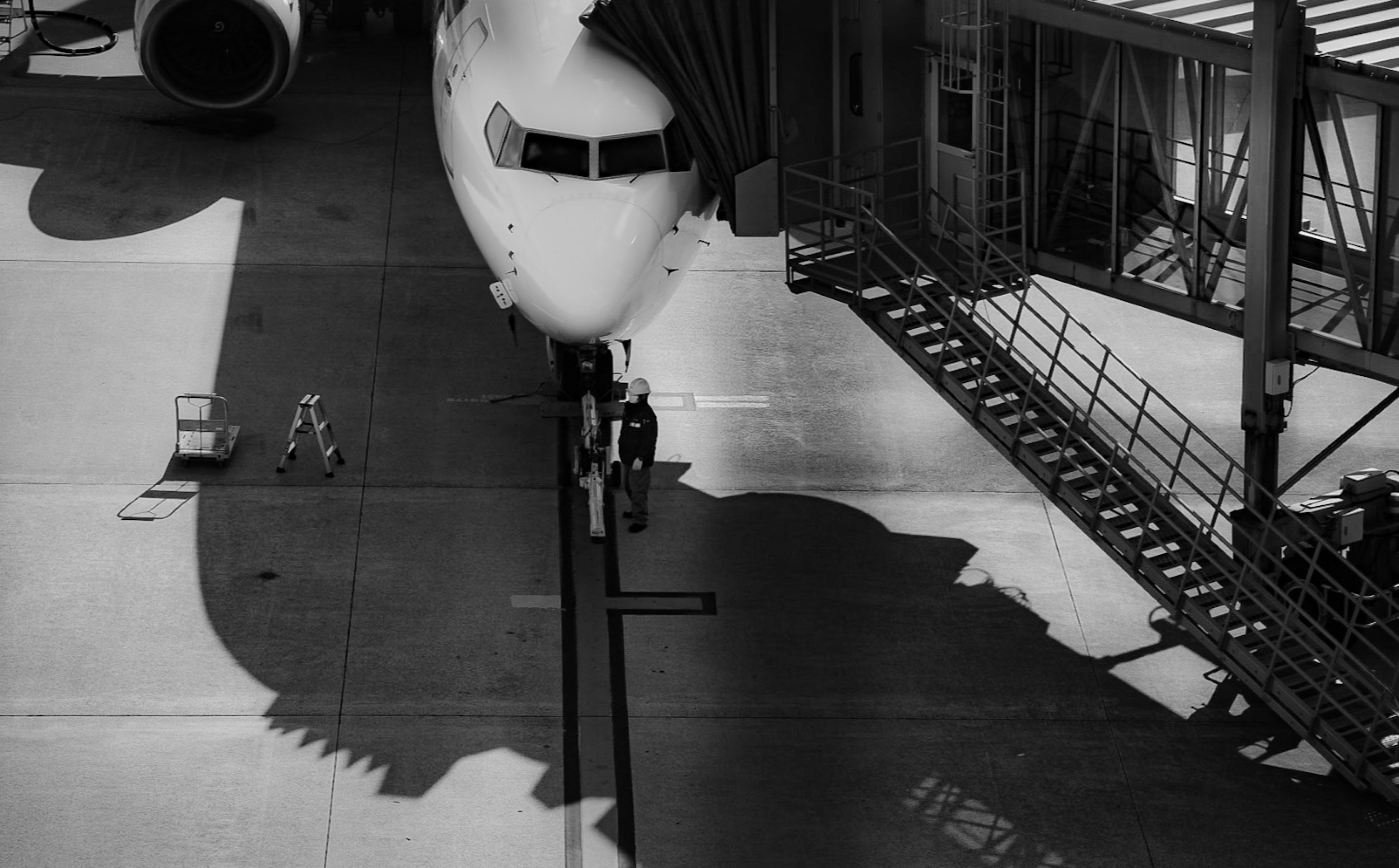 空港の滑走路に停まっている航空機の影が映るモノクロ画像