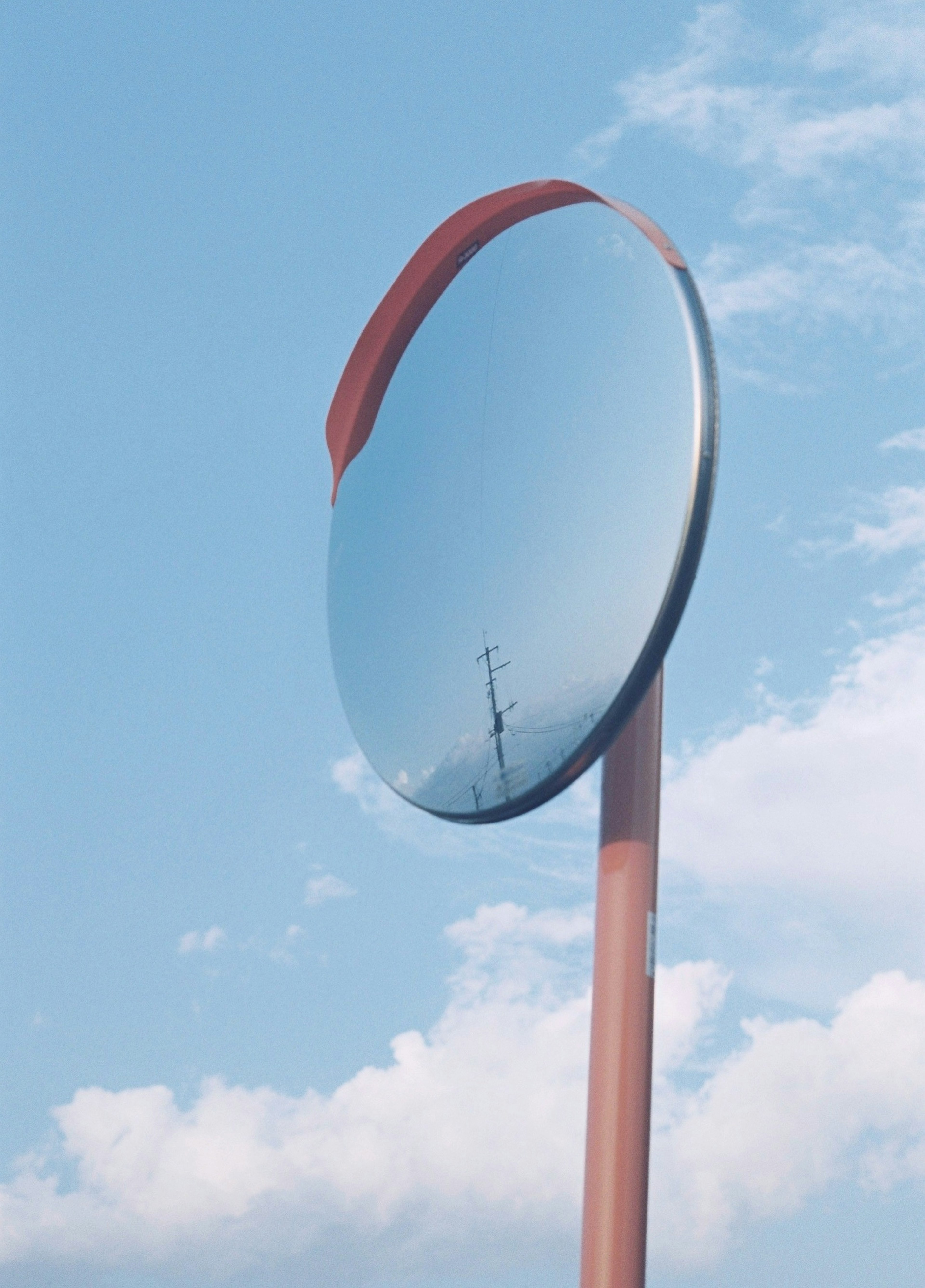 Großes Spiegel-Verkehrsschild unter blauem Himmel