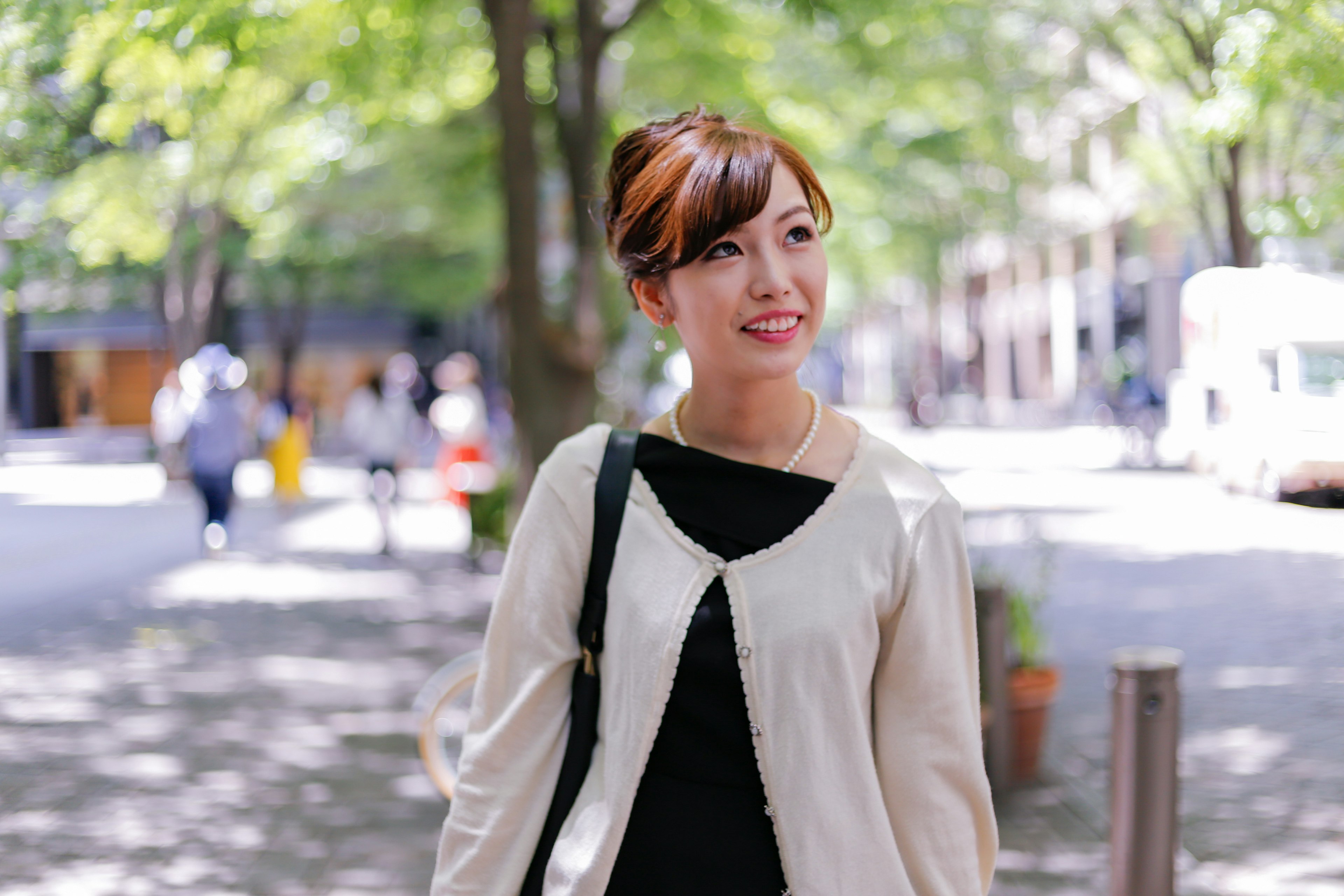 Portrait of a smiling woman in a park surrounded by green trees and bright sunlight