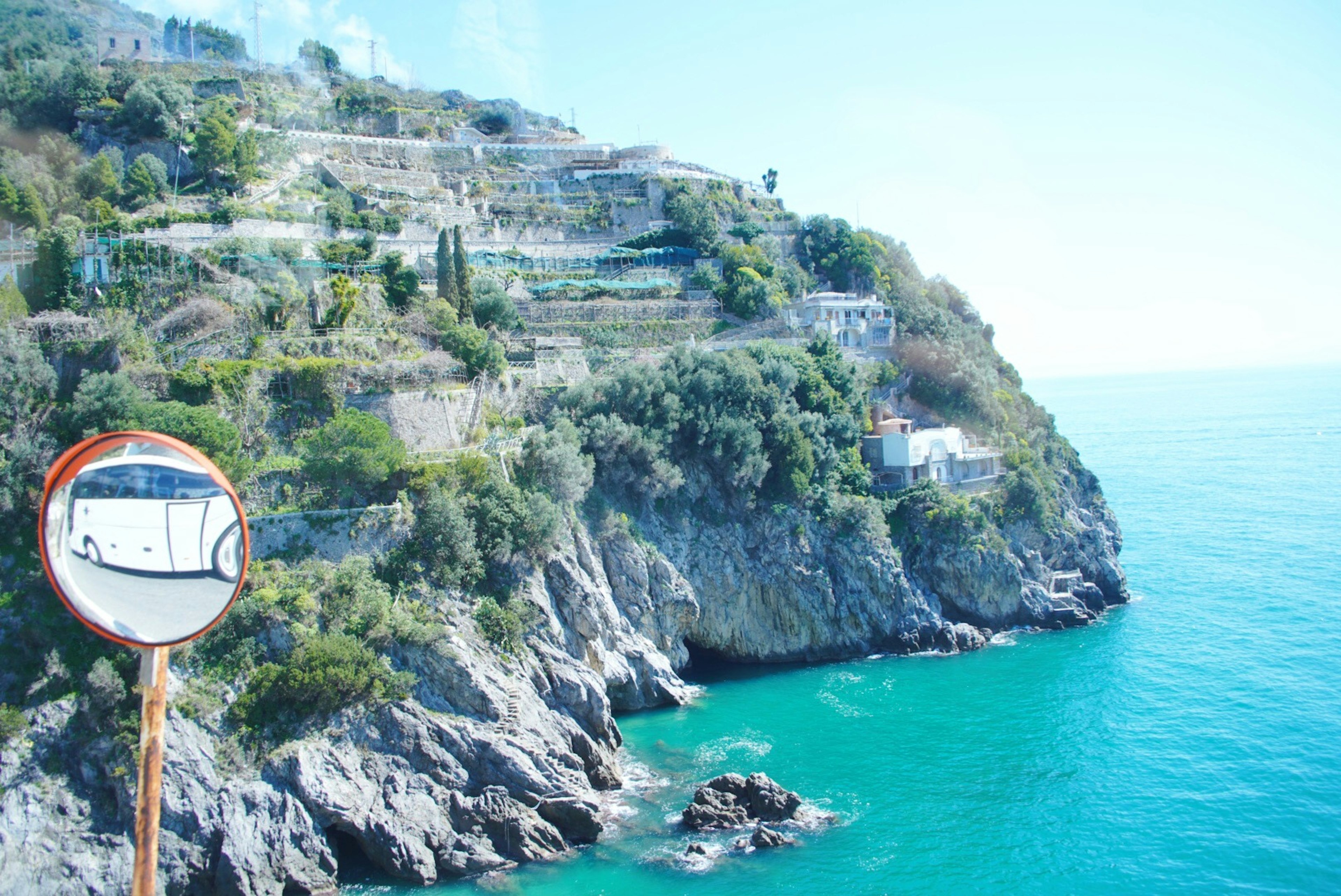 Vista del mare blu e della scogliera con uno specchio che riflette colline verdi