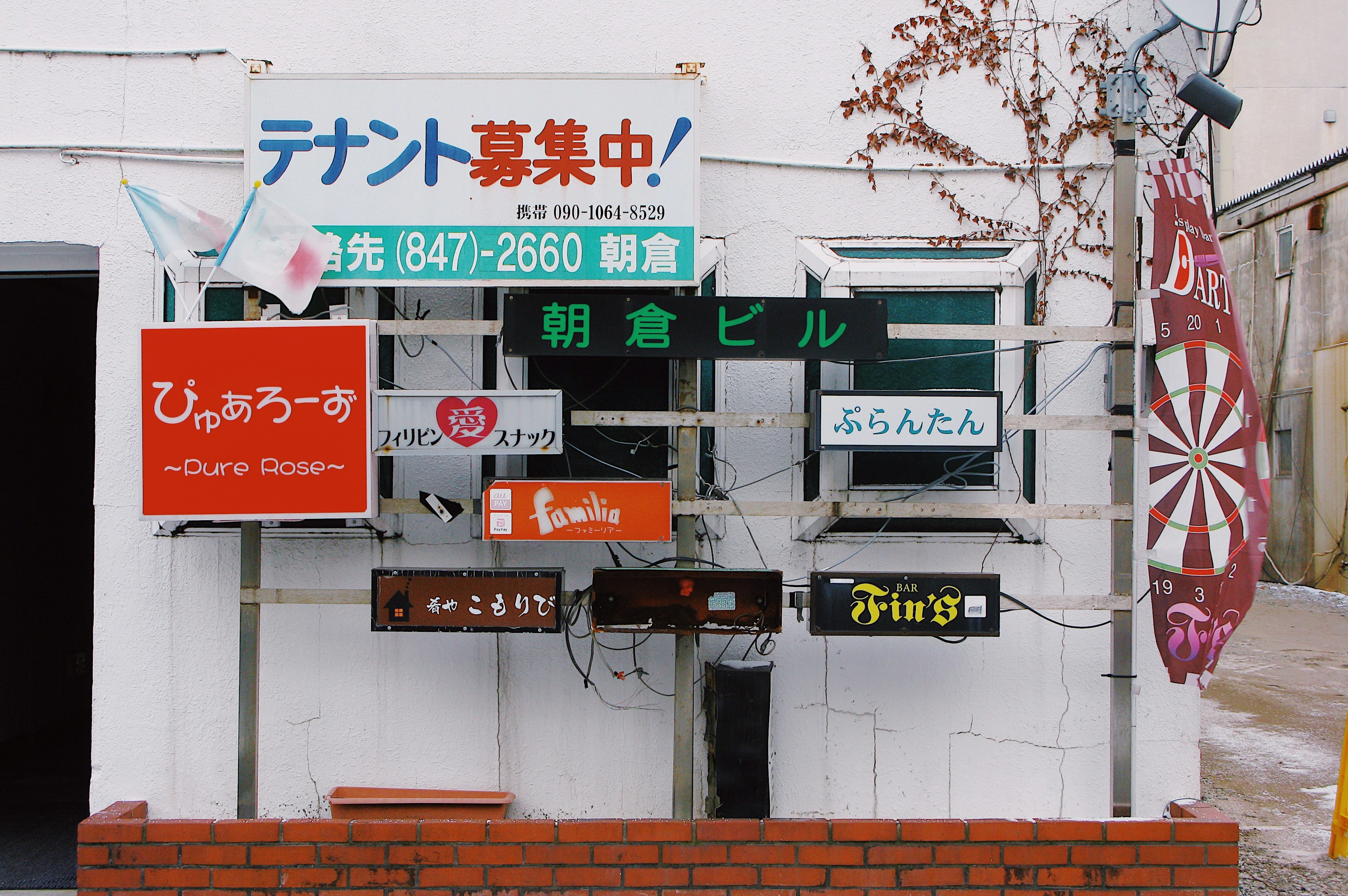 A wall displaying multiple colorful signs and advertisements for different businesses