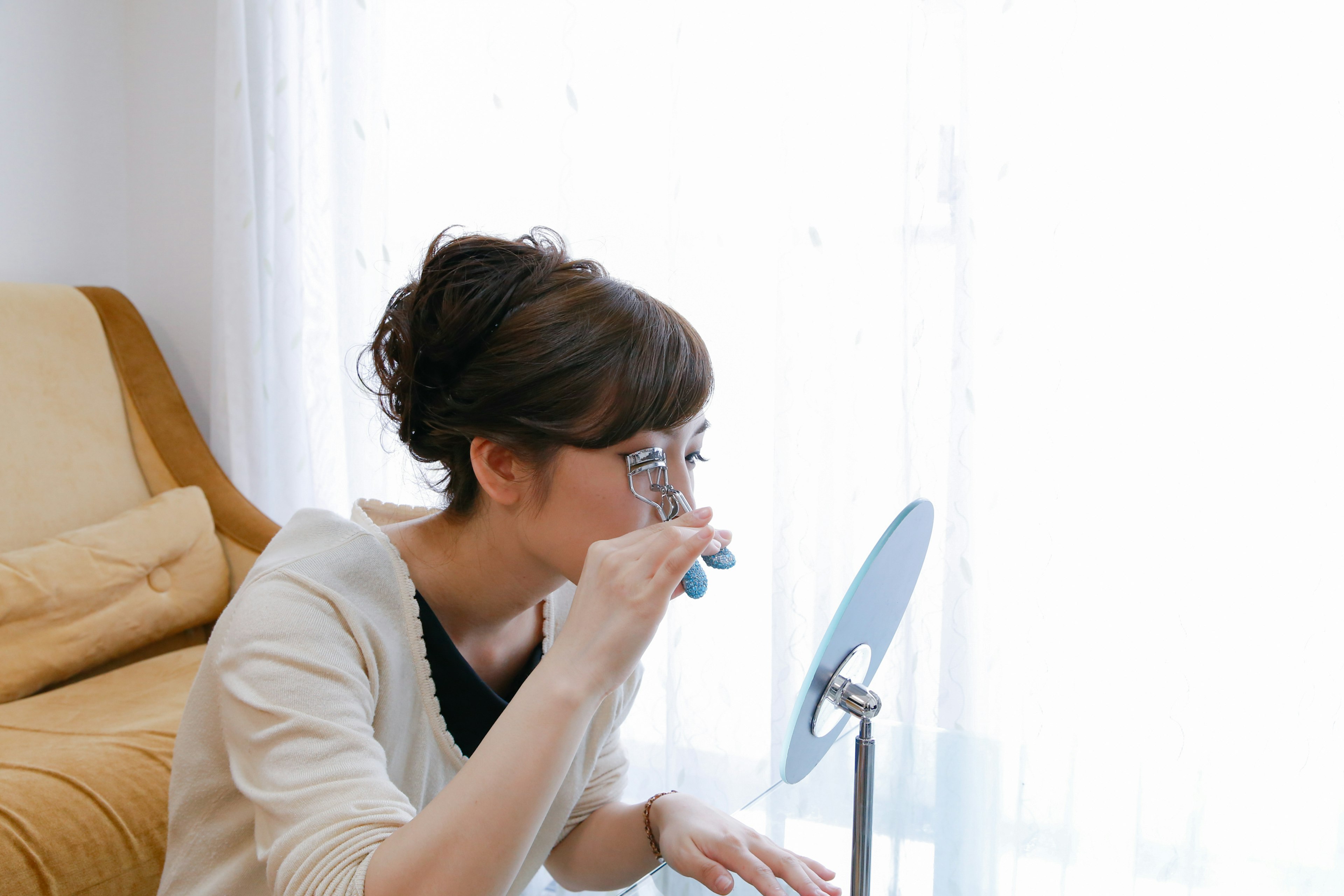 Woman grooming her eyebrows in front of a mirror indoors