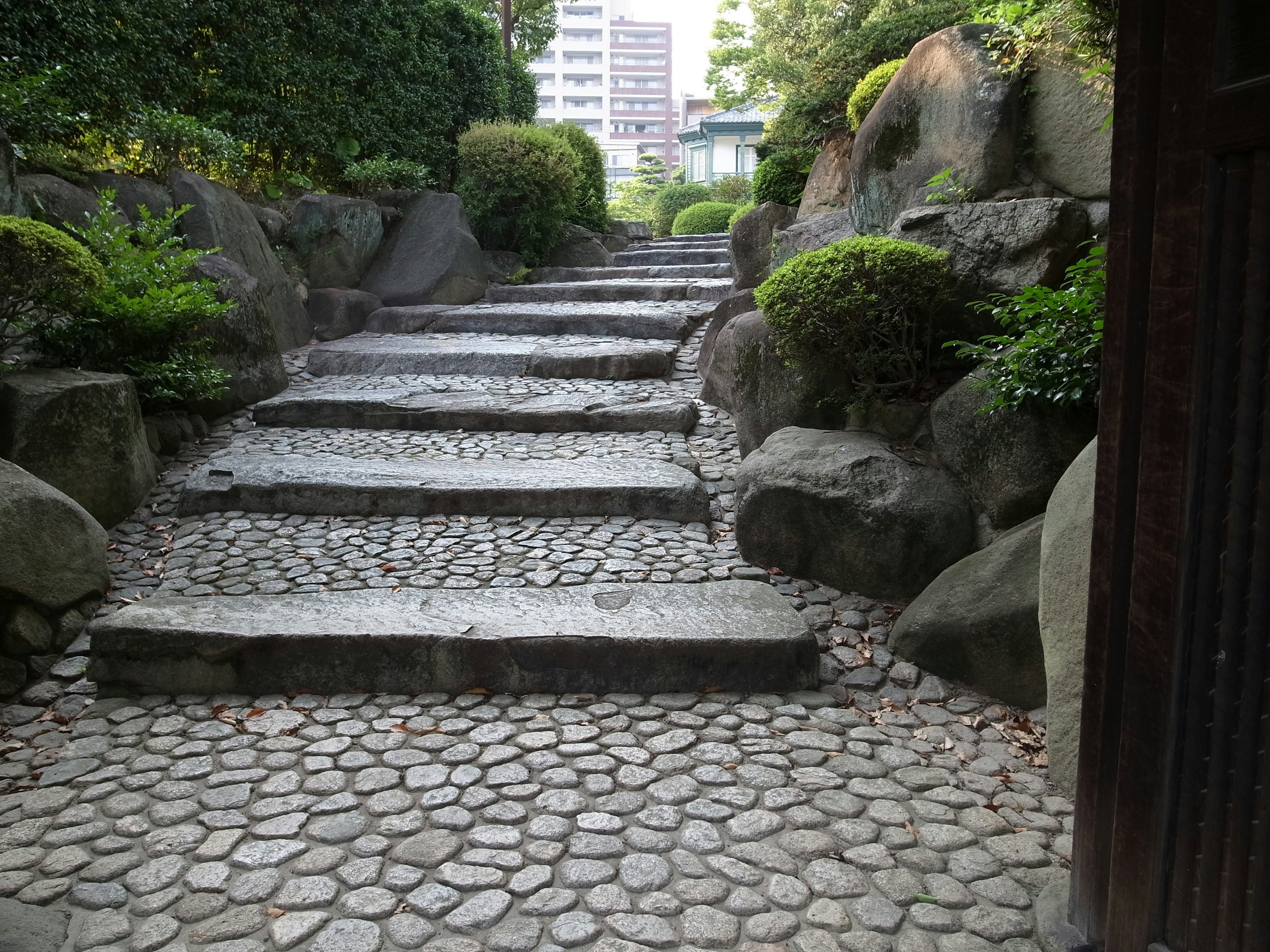 Steinige Treppen, die durch einen ruhigen Garten mit Grün führen